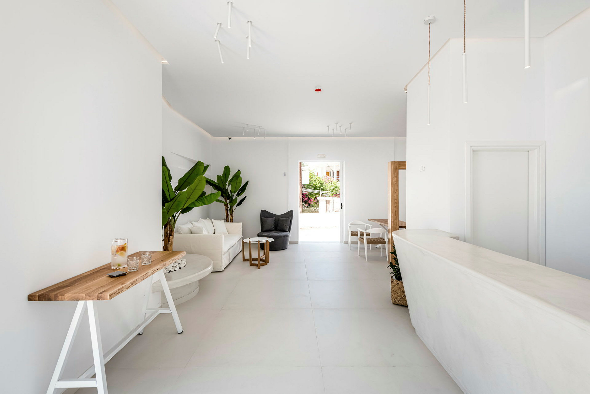 Et lyst og minimalistisk innredet rom med hvite møbler og grønne planter. (AI-generert tekst)