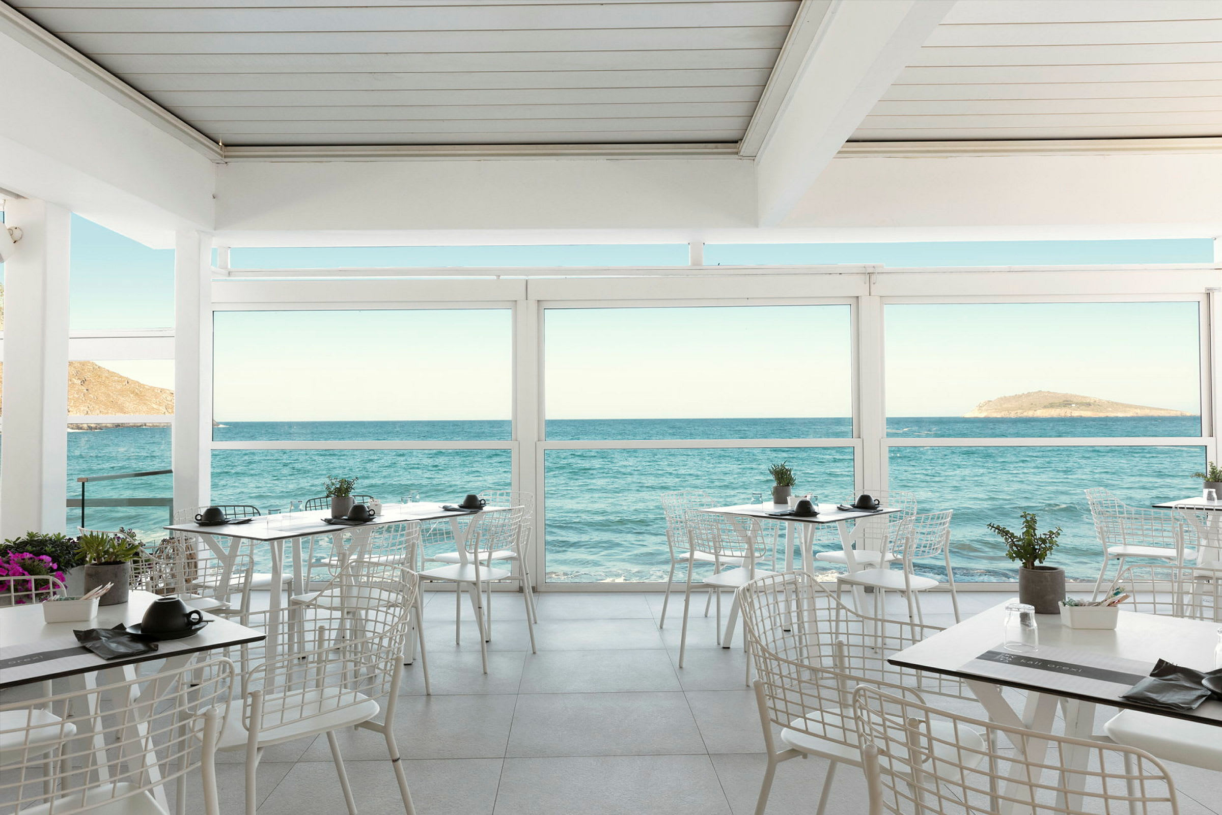 Restaurant med utsikt over havet gjennom store vinduer. (AI-generert tekst)