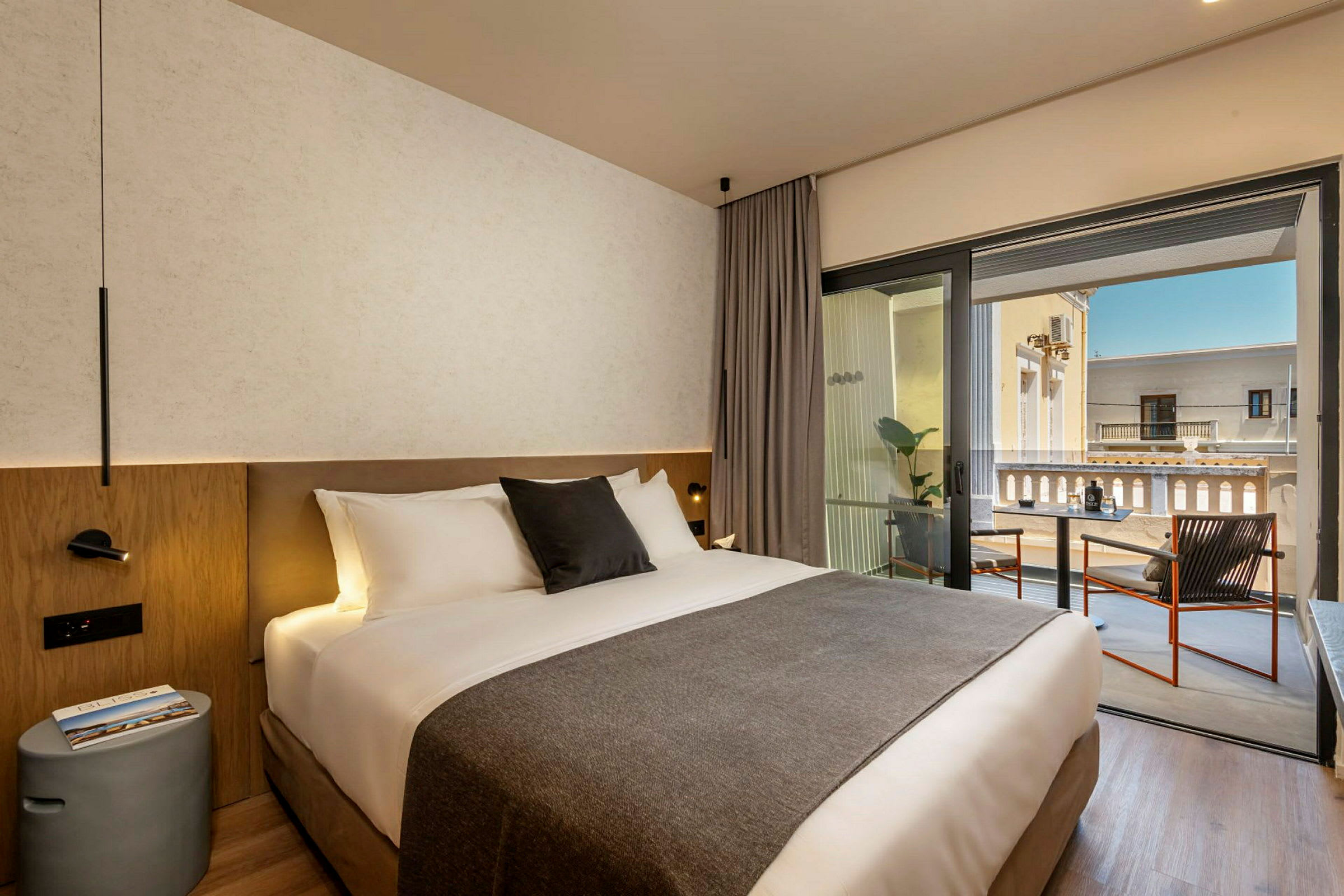 Et hotellrom med en dobbeltseng og en balkong med sitteplasser. (AI-generert tekst)