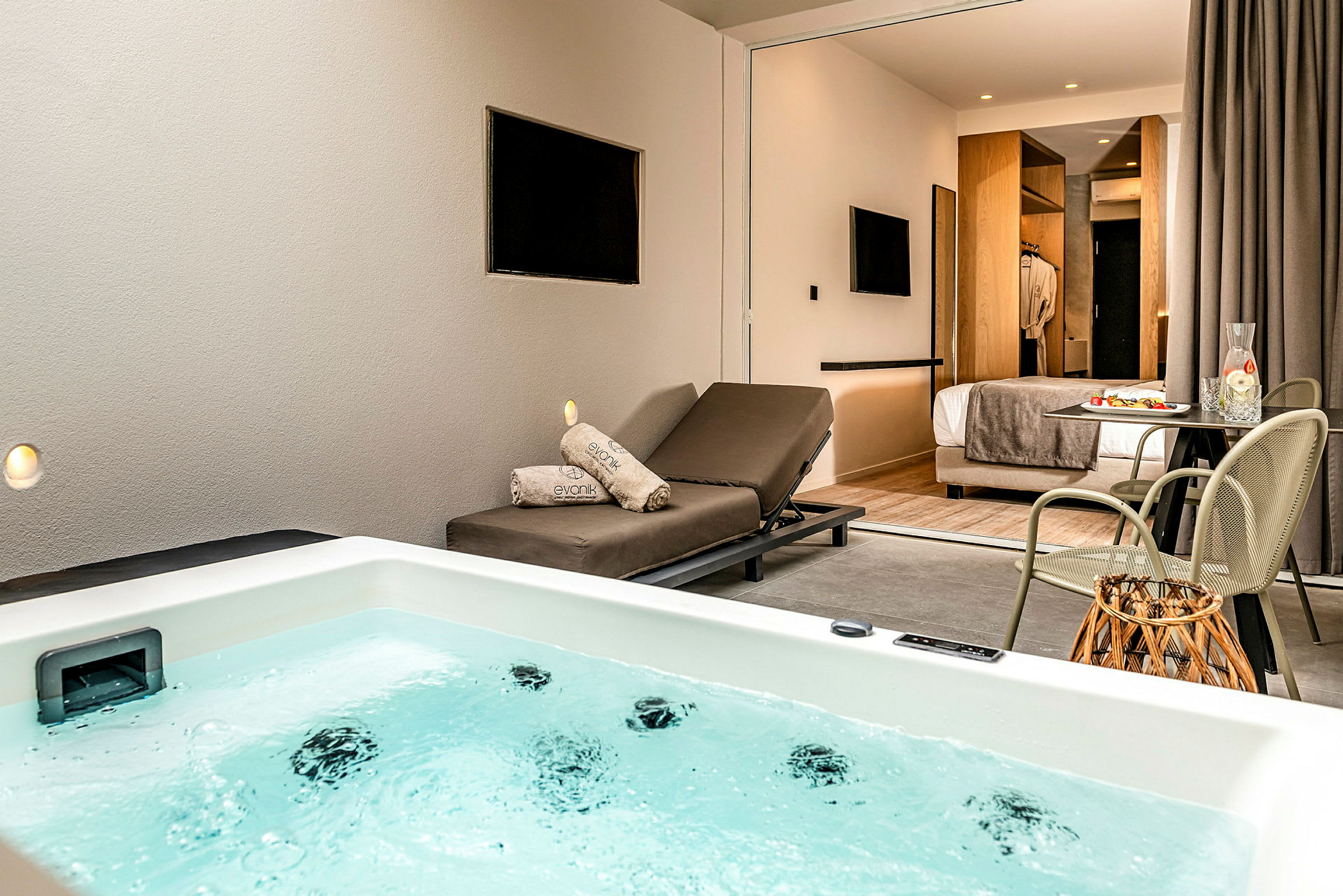 Et hotellrom med egen badekar i forgrunnen og en solseng samt spisebord på rommet. (AI-generert tekst)