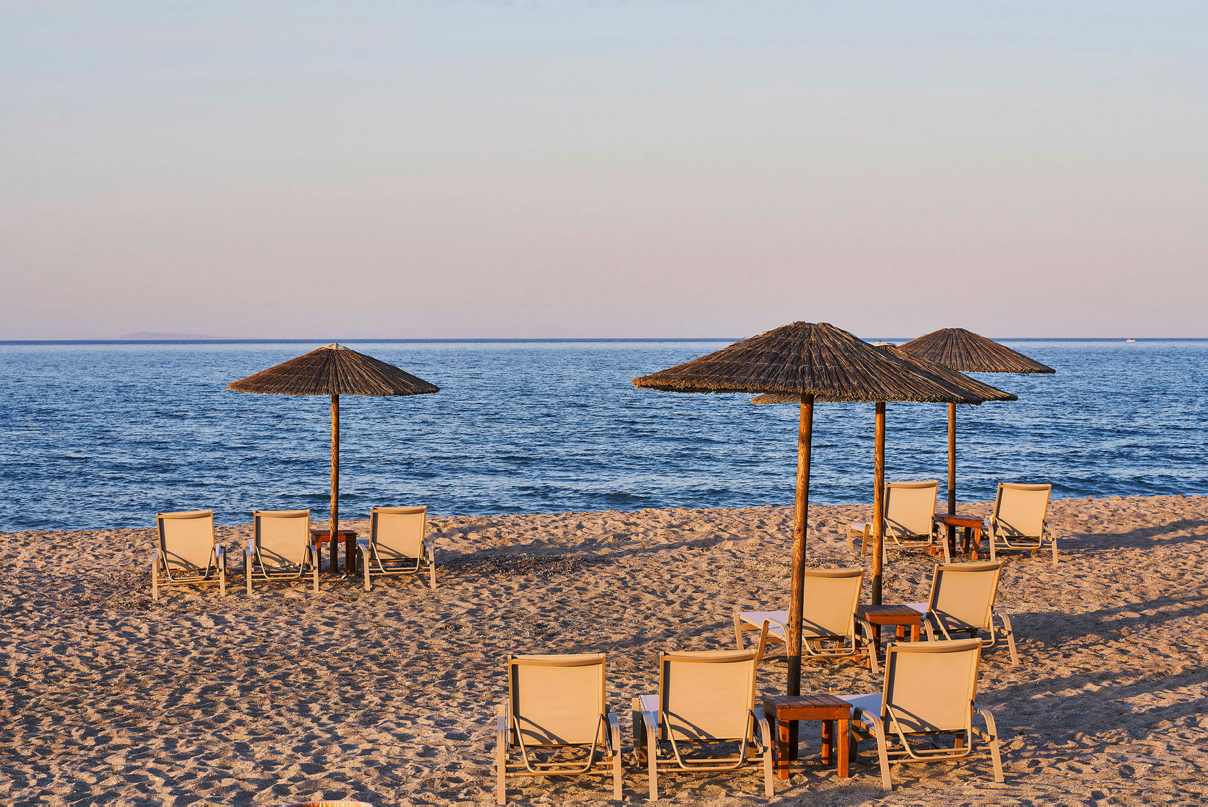 Strand med solsenger og parasoller ved vannet. (AI-generert tekst)