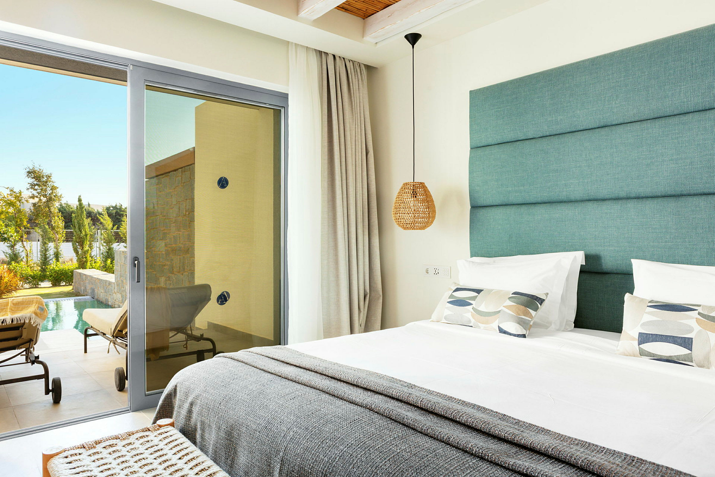 Viser et moderne hotellrom med en dobbeltseng og en glassdør som fører til en terrasse med solsenger ved et basseng. (AI-generert tekst)
