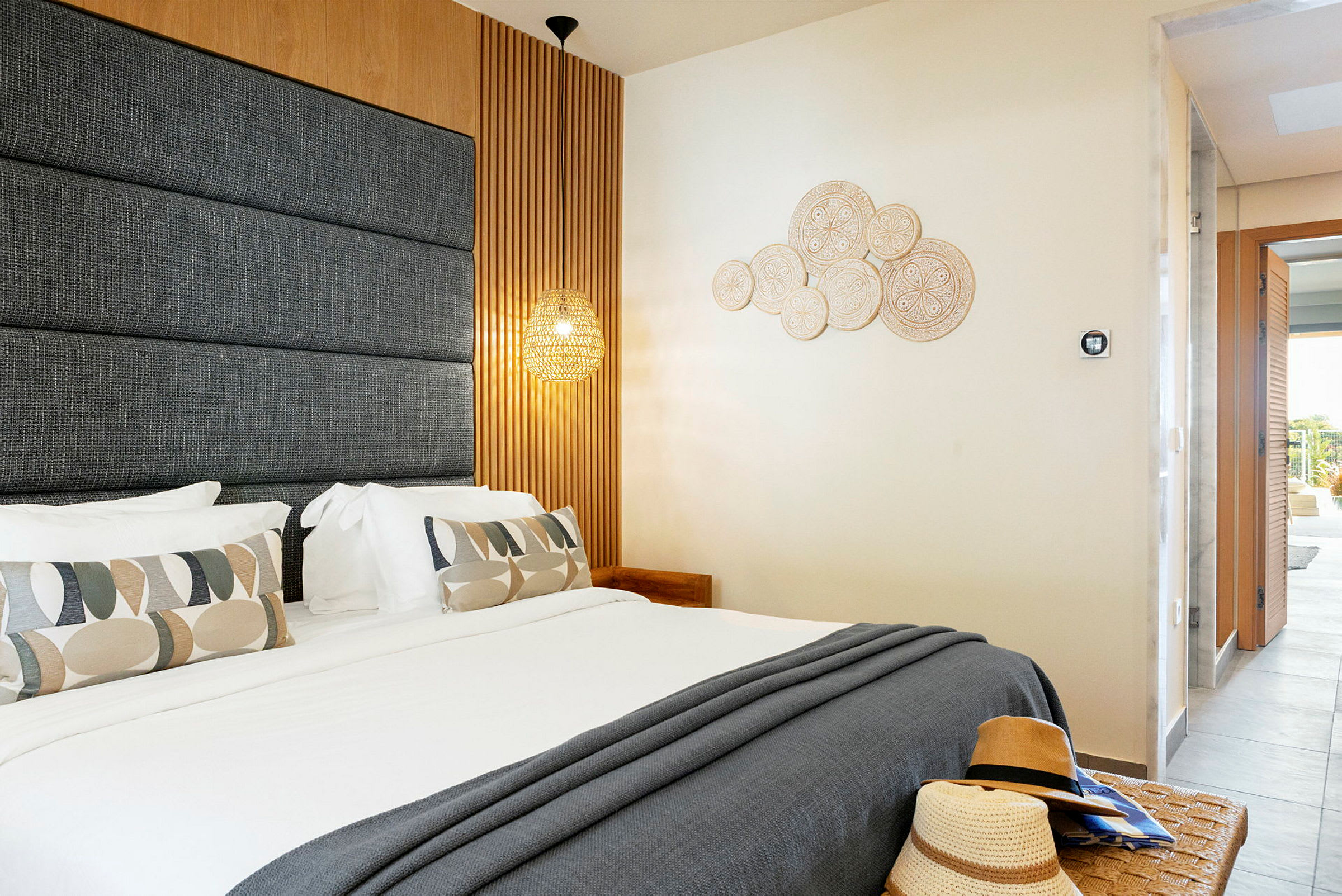 Et moderne innredet hotellrom med en dobbeltseng, dekorative puter og veggdetaljer. (AI-generert tekst)