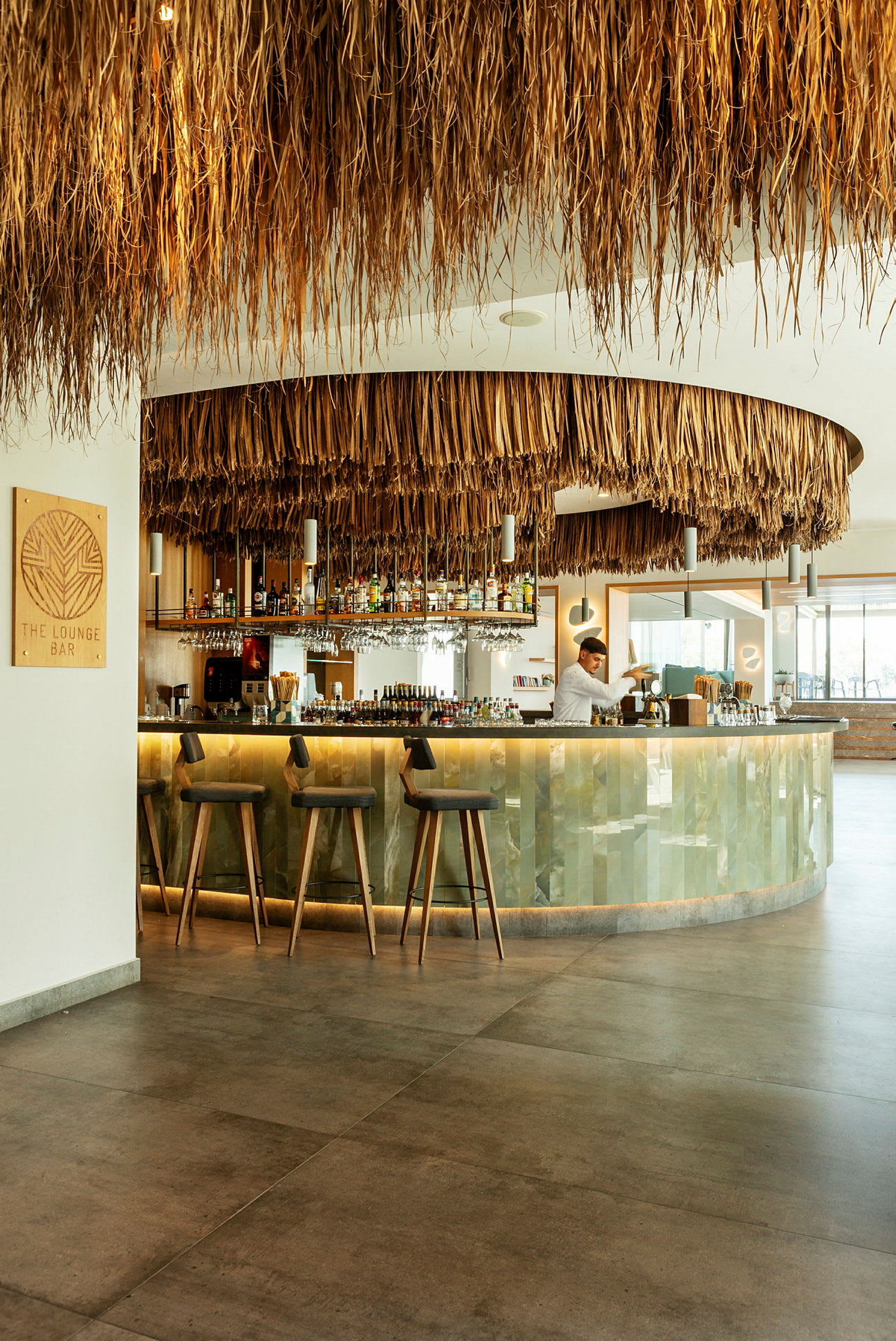 En moderne loungebar med et tak dekorert med naturlige materialer og en godt utstyrt bardisk. (AI-generert tekst)
