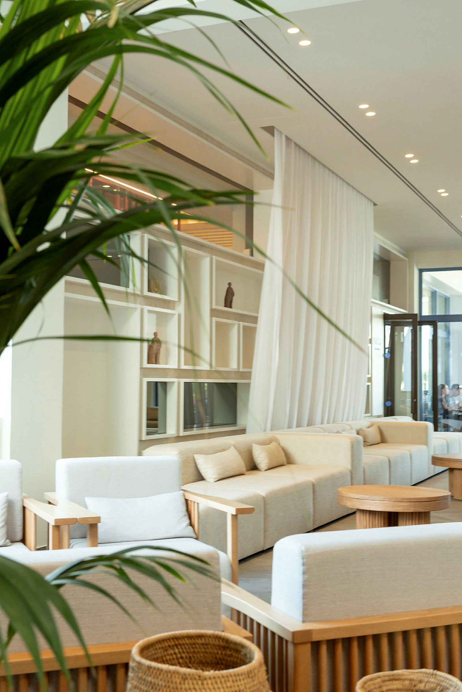 Lyst og elegant lobby med komfortable sofaer og stoler i nøytrale farger, lave trebord og dekorative hyller i bakgrunnen. (AI-generert tekst)