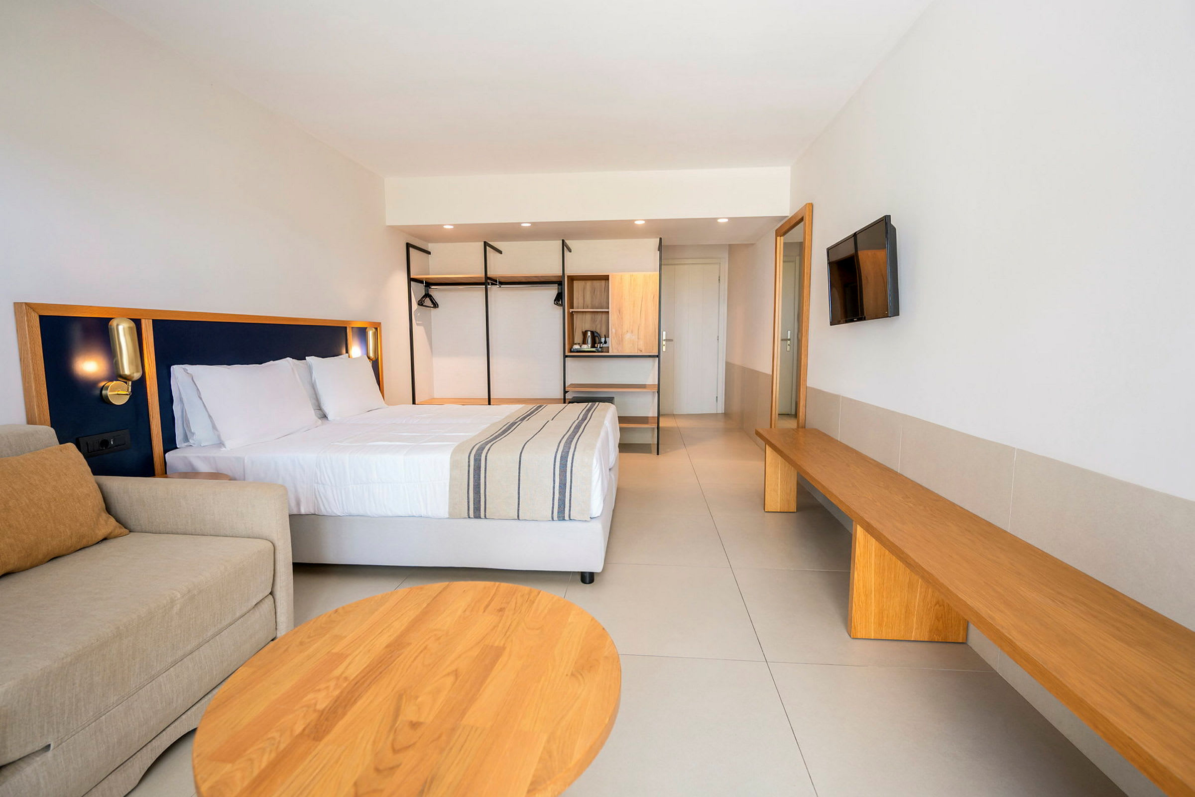Et moderne hotellrom med en dobbeltseng, sofa og treinteriør. (AI-generert tekst)