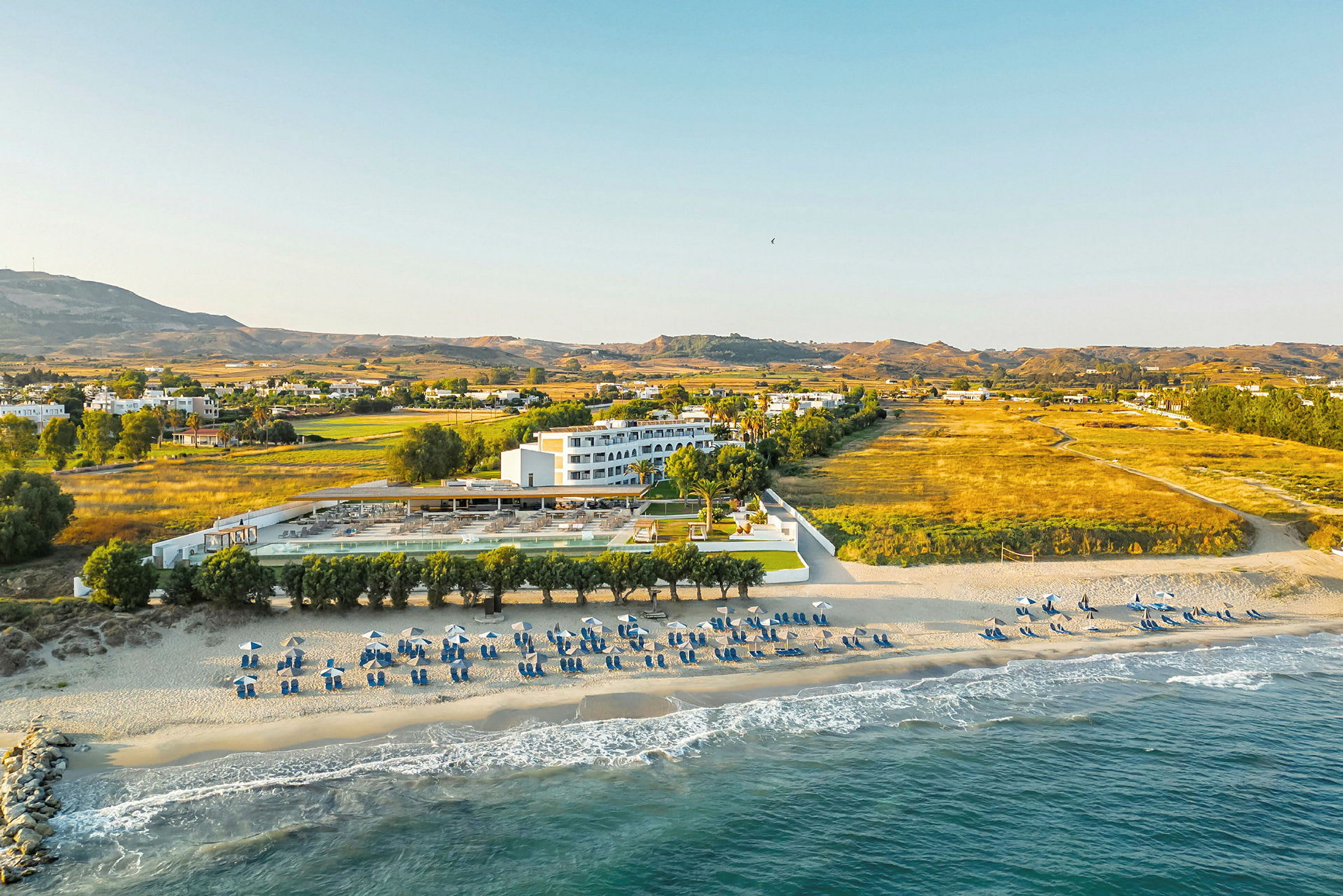 Strand og hotell med omkringliggende landskap. (AI-generert tekst)