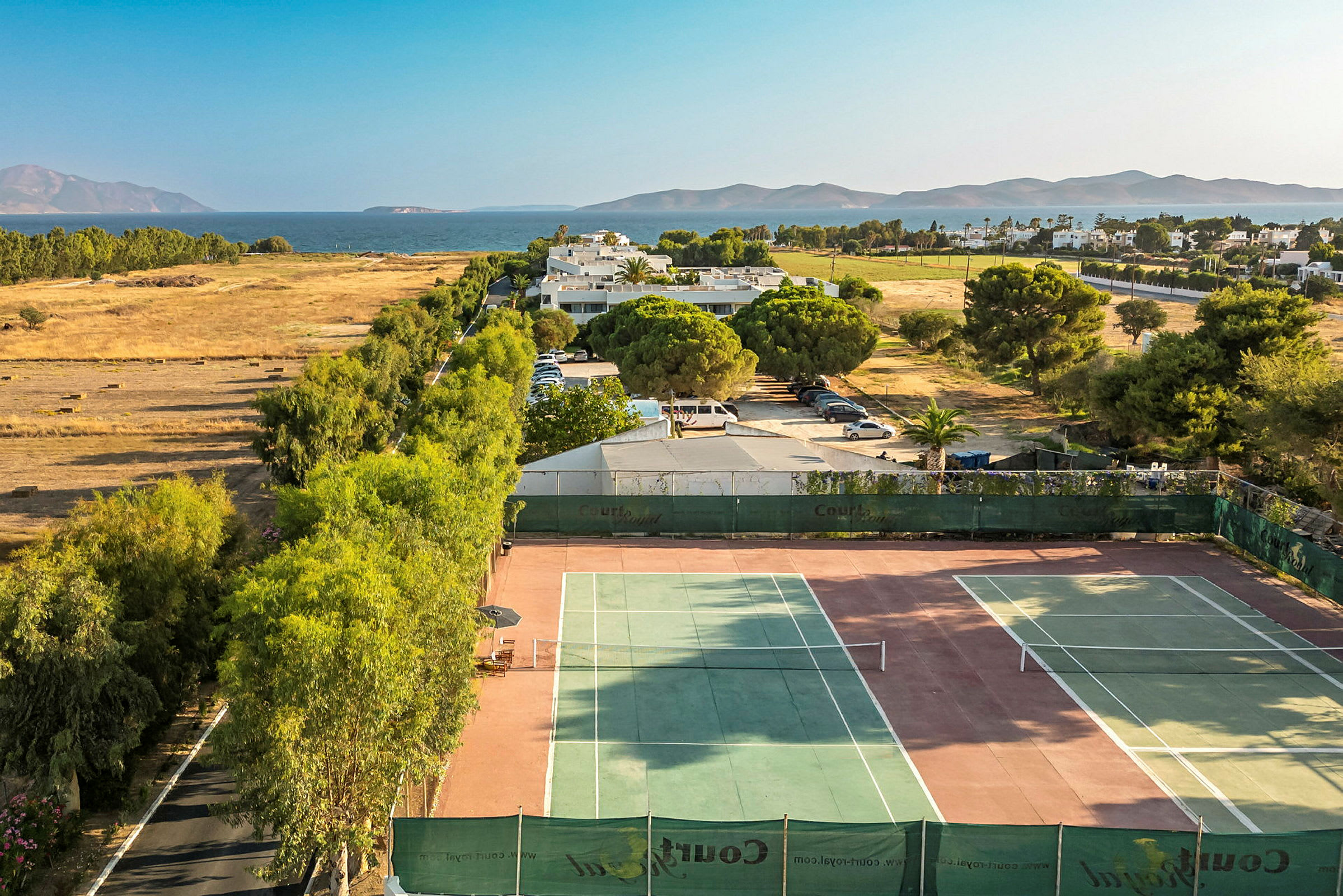 Tennisbaner med landskap og hav i bakgrunnen. (AI-generert tekst)