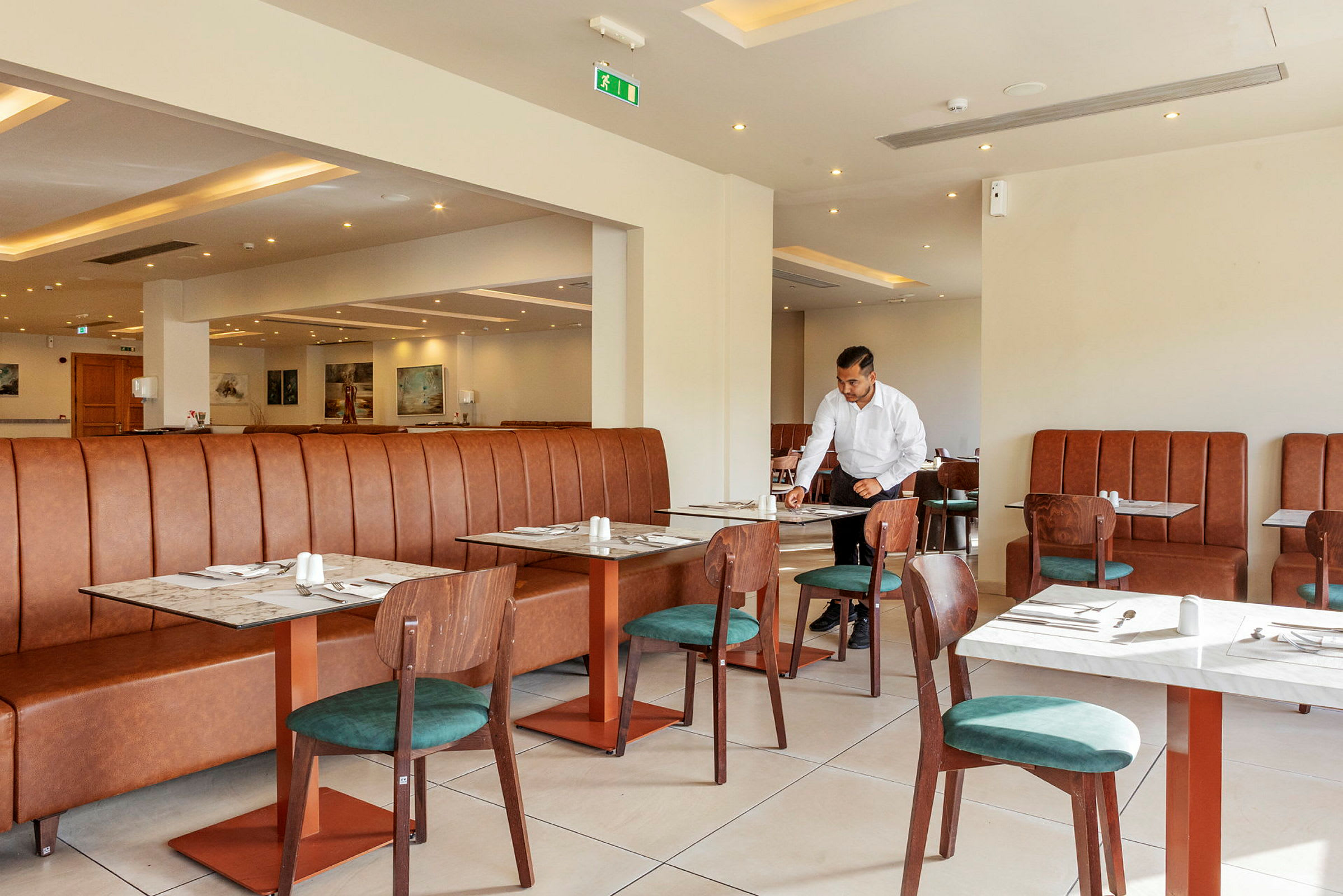 Interiør av en restaurant med bord og stoler samt en brun skinnsofa. (AI-generert tekst)