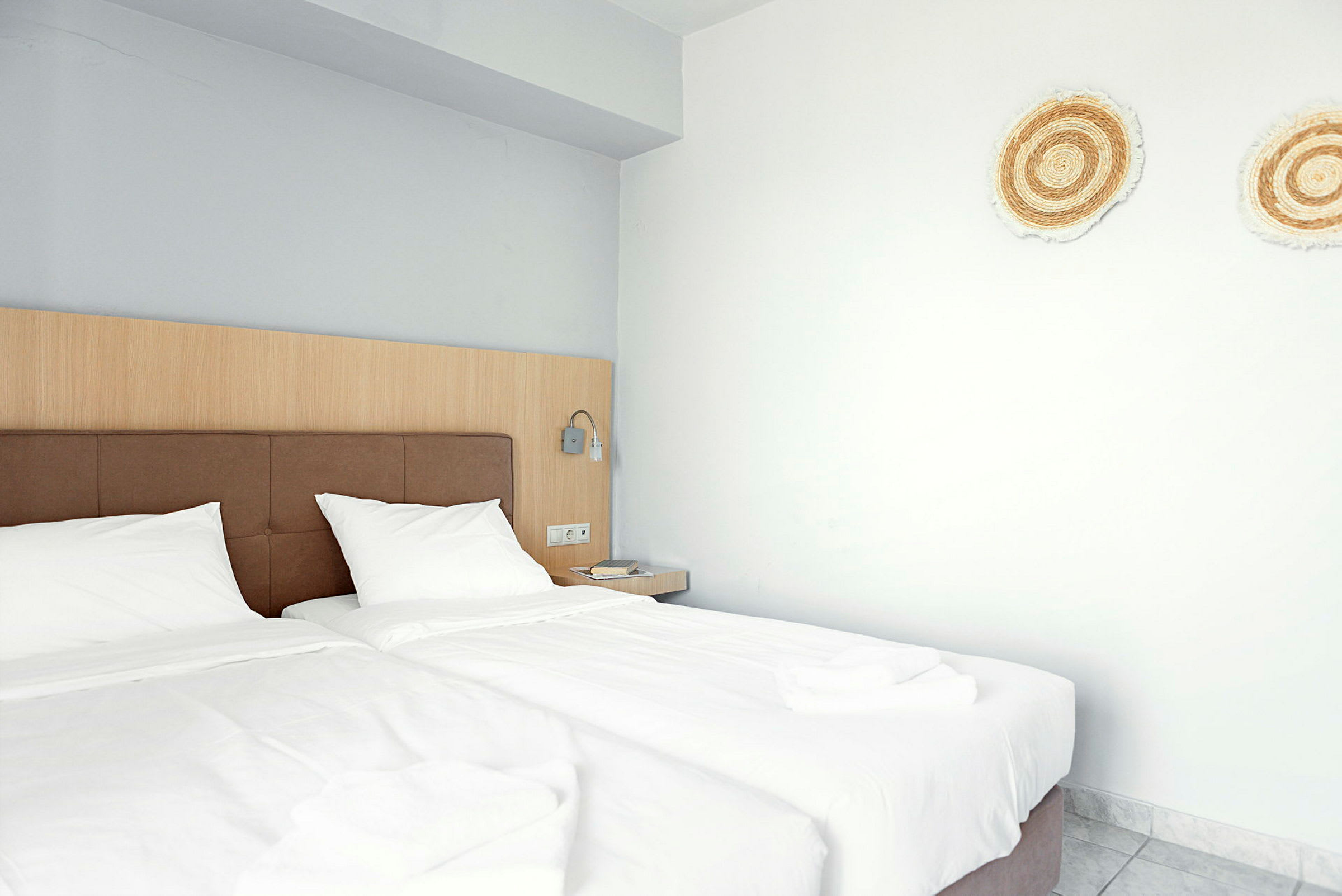 Hotellrom med to enkeltsenger og dekorasjoner på veggen. (AI-generert tekst)
