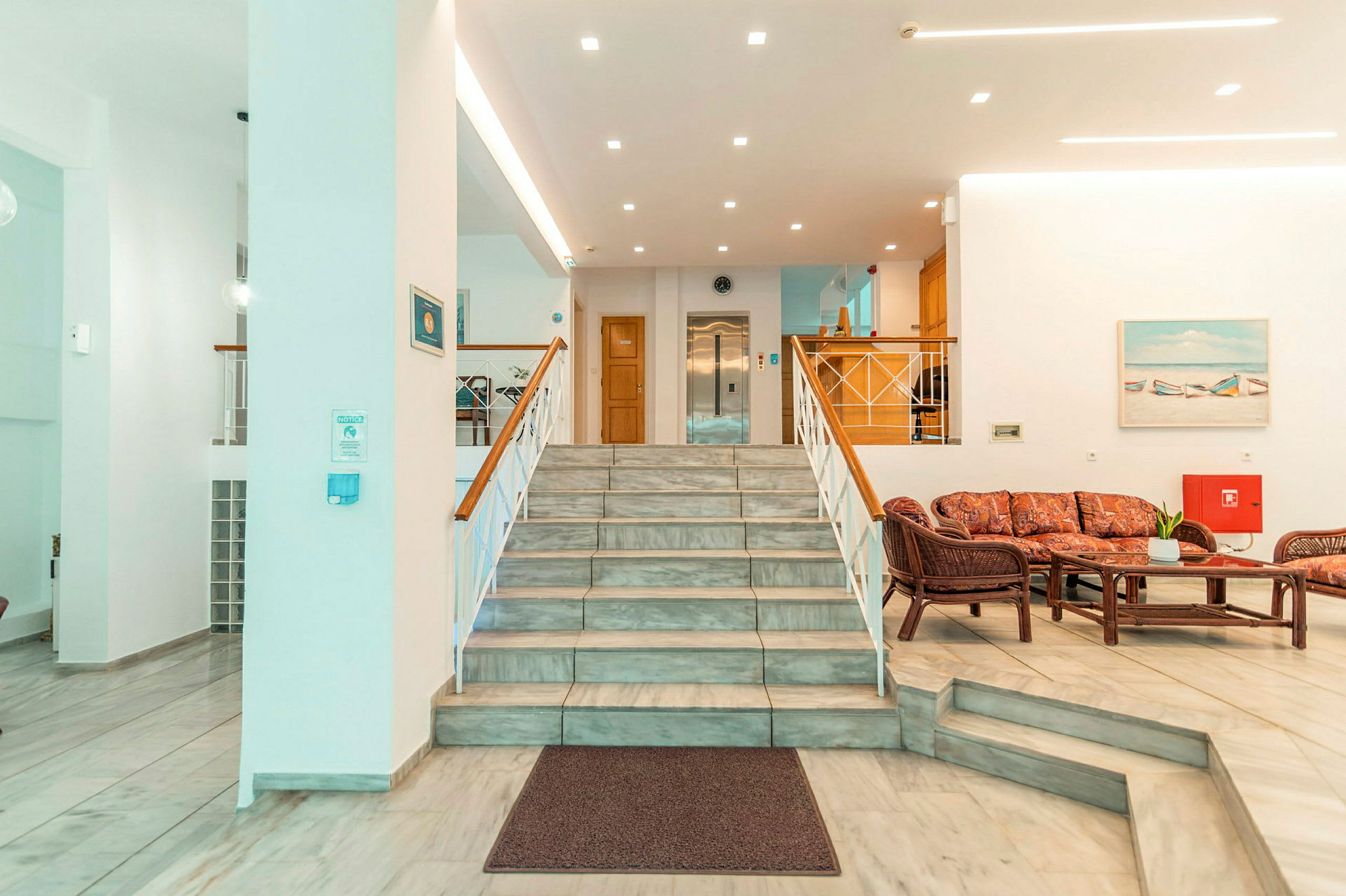 Hotellobbyen med en trapp, sittegruppe og resepsjon. (AI-generert tekst)