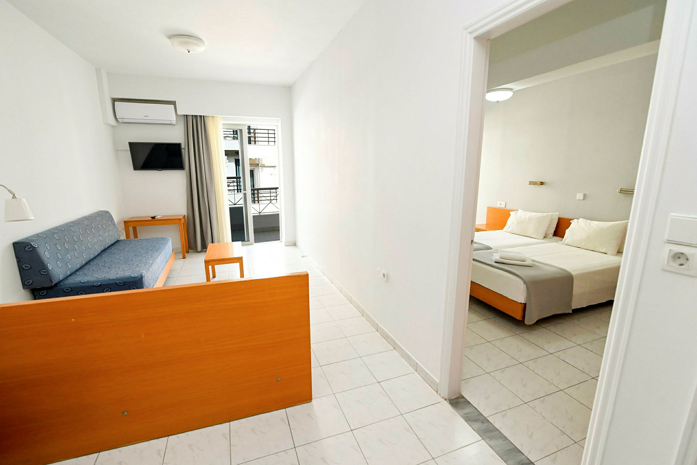 Et hotellrom med en stuedel som inneholder en blå sofa og bord samt en soveromsdel med en dobbeltseng. (AI-generert tekst)