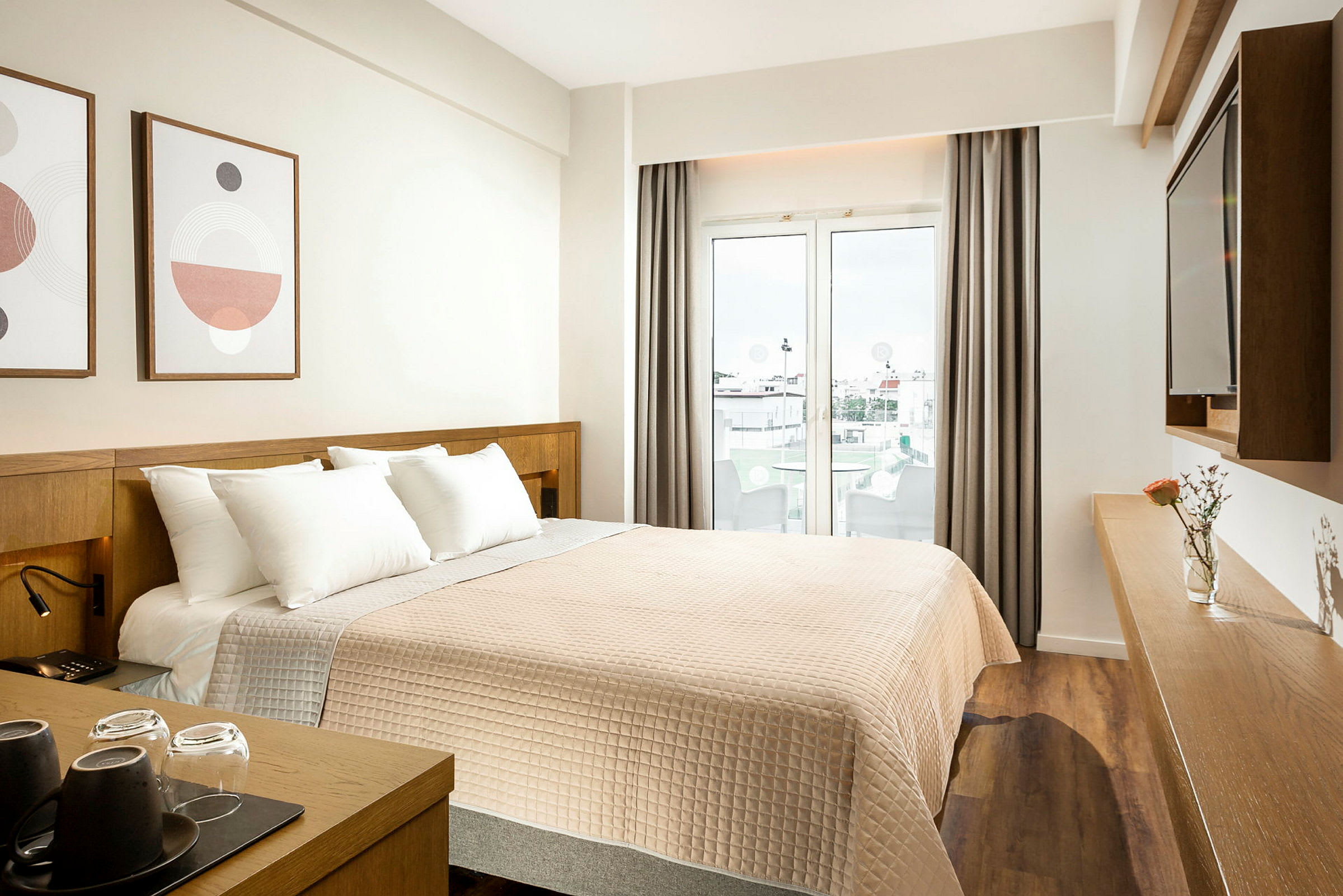 Hotellrom med en dobbeltseng, dekor på veggen, og en glassdør som fører ut til en balkong. (AI-generert tekst)