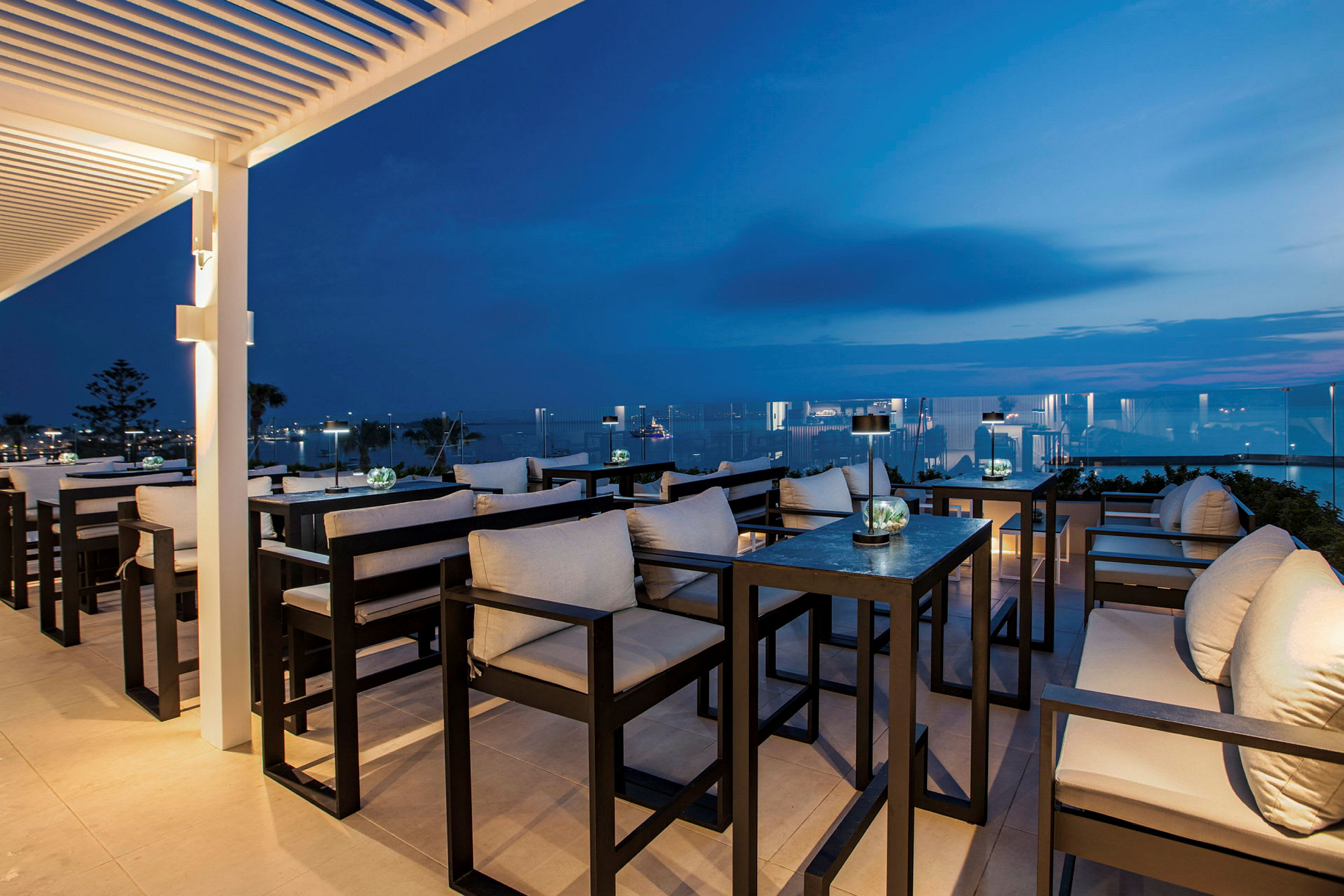 Elegant terrasse-lounge med sitteplasser og utsikt over nattehimmelen og havet. (AI-generert tekst)