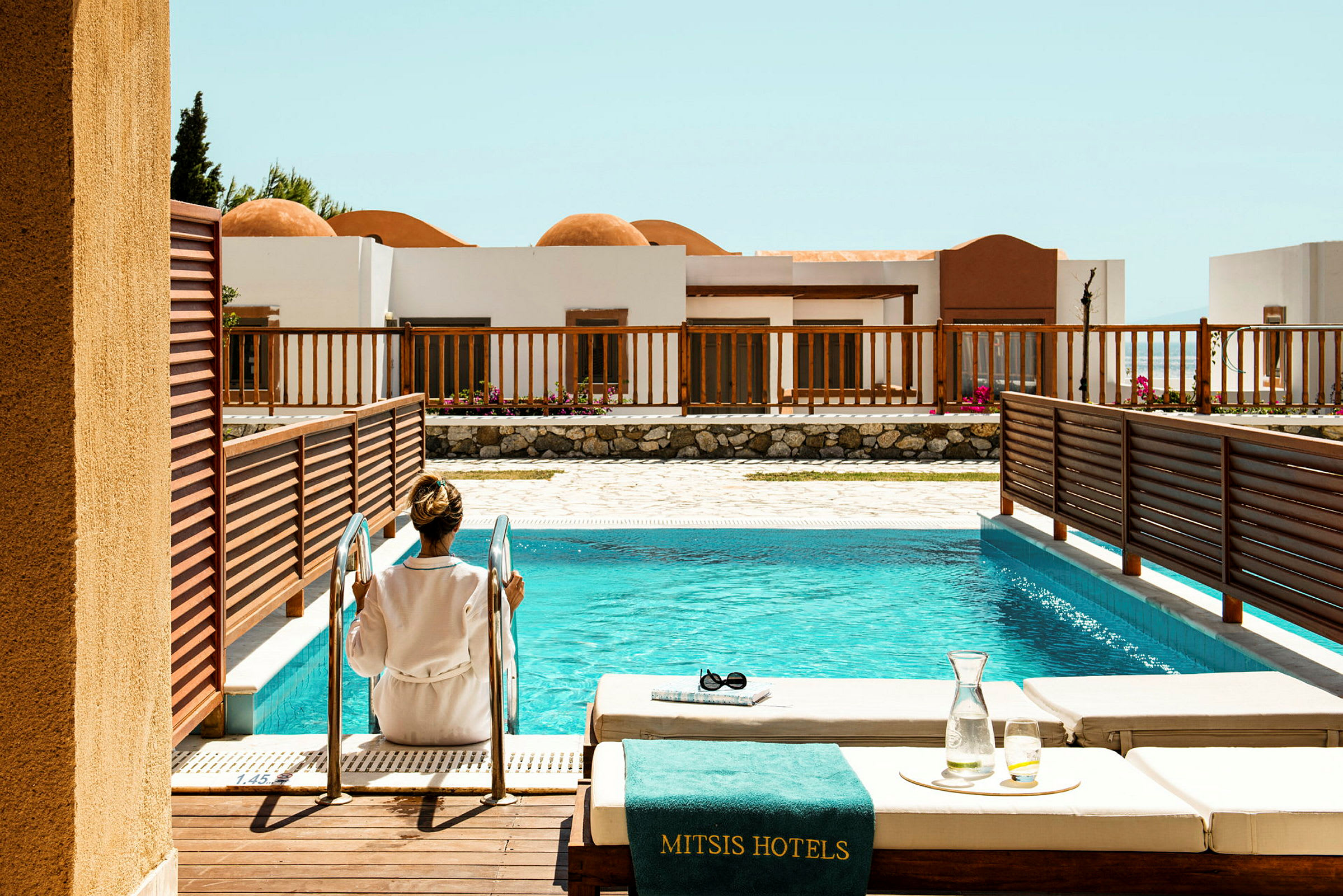 En person sitter ved trappen til et hotellbasseng. (AI-generert tekst)