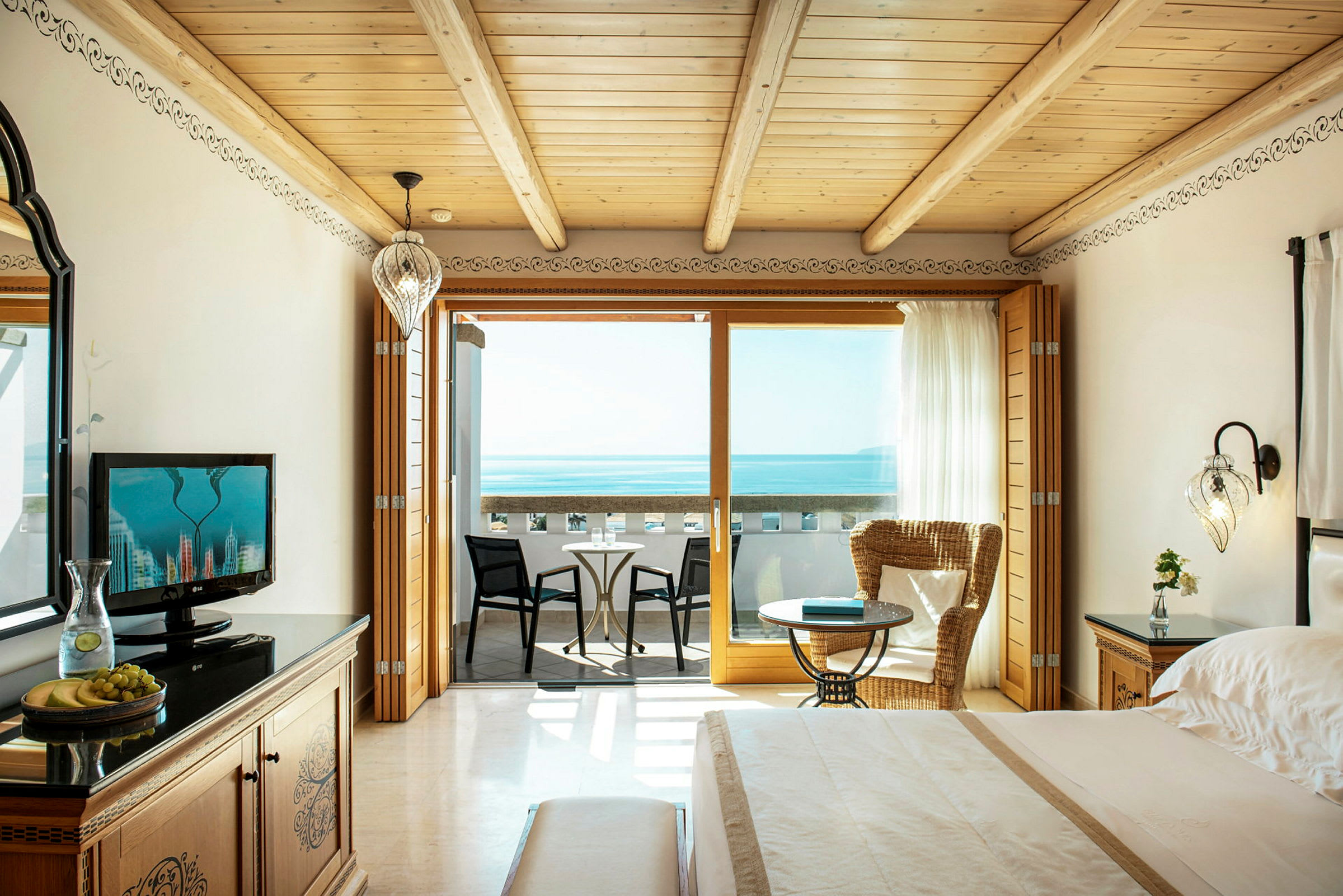 Et hotellrom med utsikt over havet, inkludert en balkong med sitteplasser. (AI-generert tekst)
