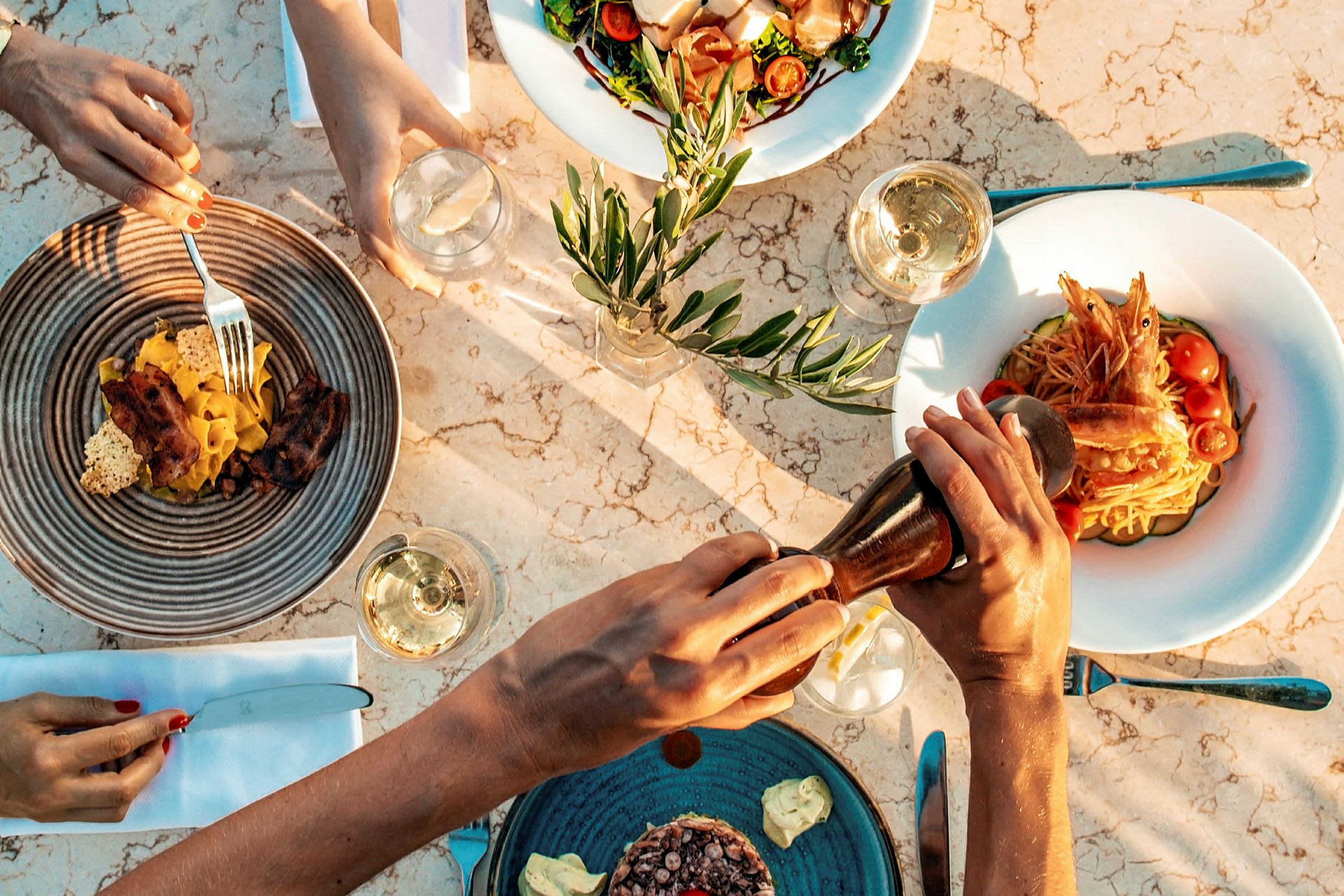 Fire tallerkener med forskjellige retter og glass med drikke på et marmorbord. (AI-generert tekst)