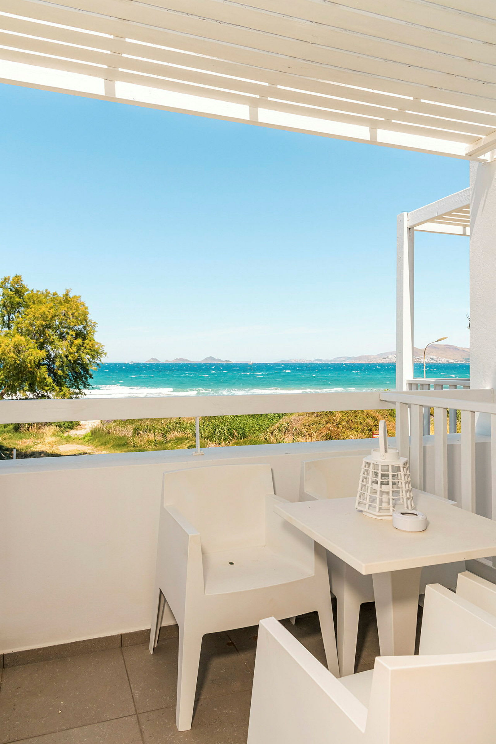 En terrasse med hvite møbler og utsikt over havet. (AI-generert tekst)