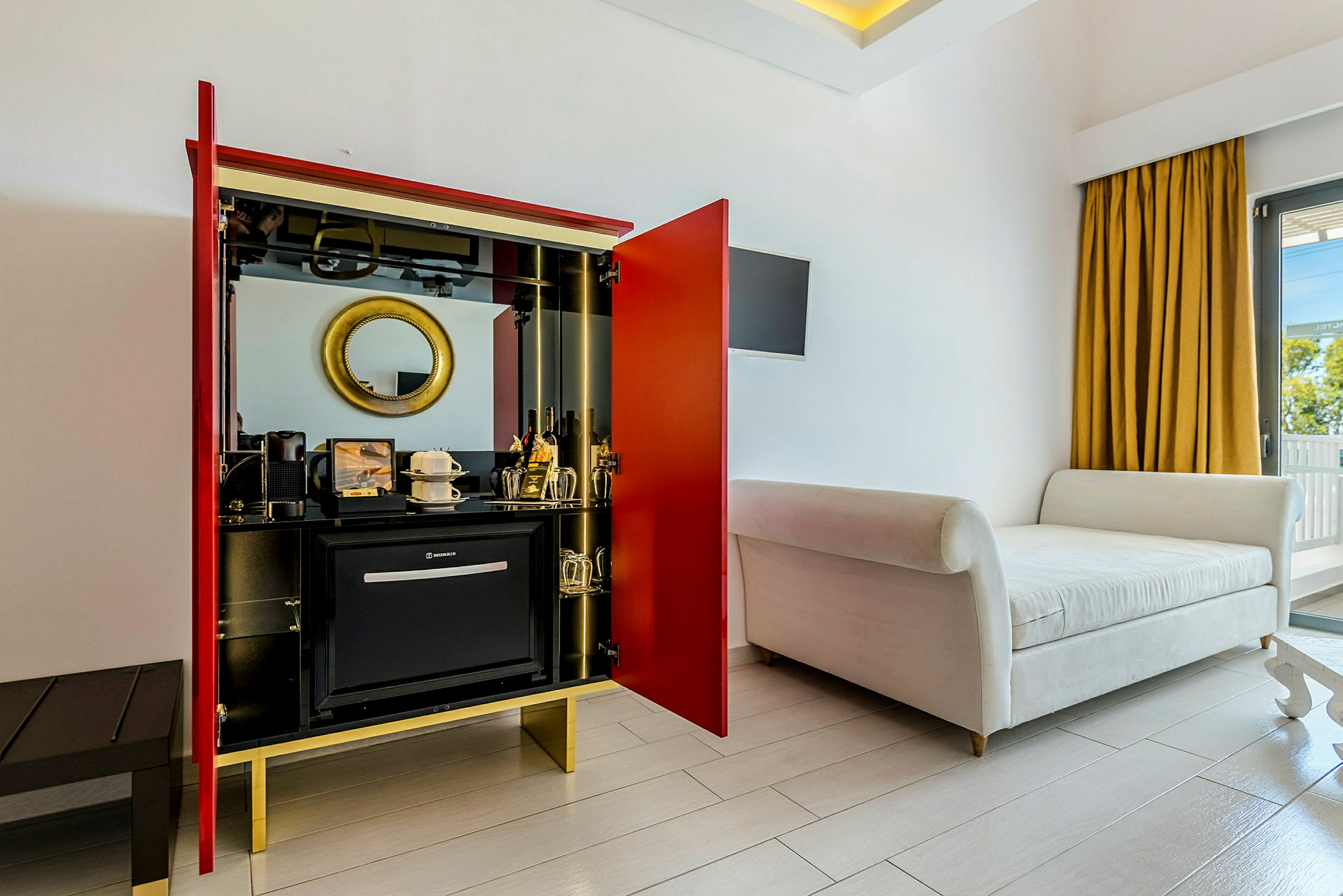 Hotellrom med en sittemøbel, garderobe og minibar. (AI-generert tekst)