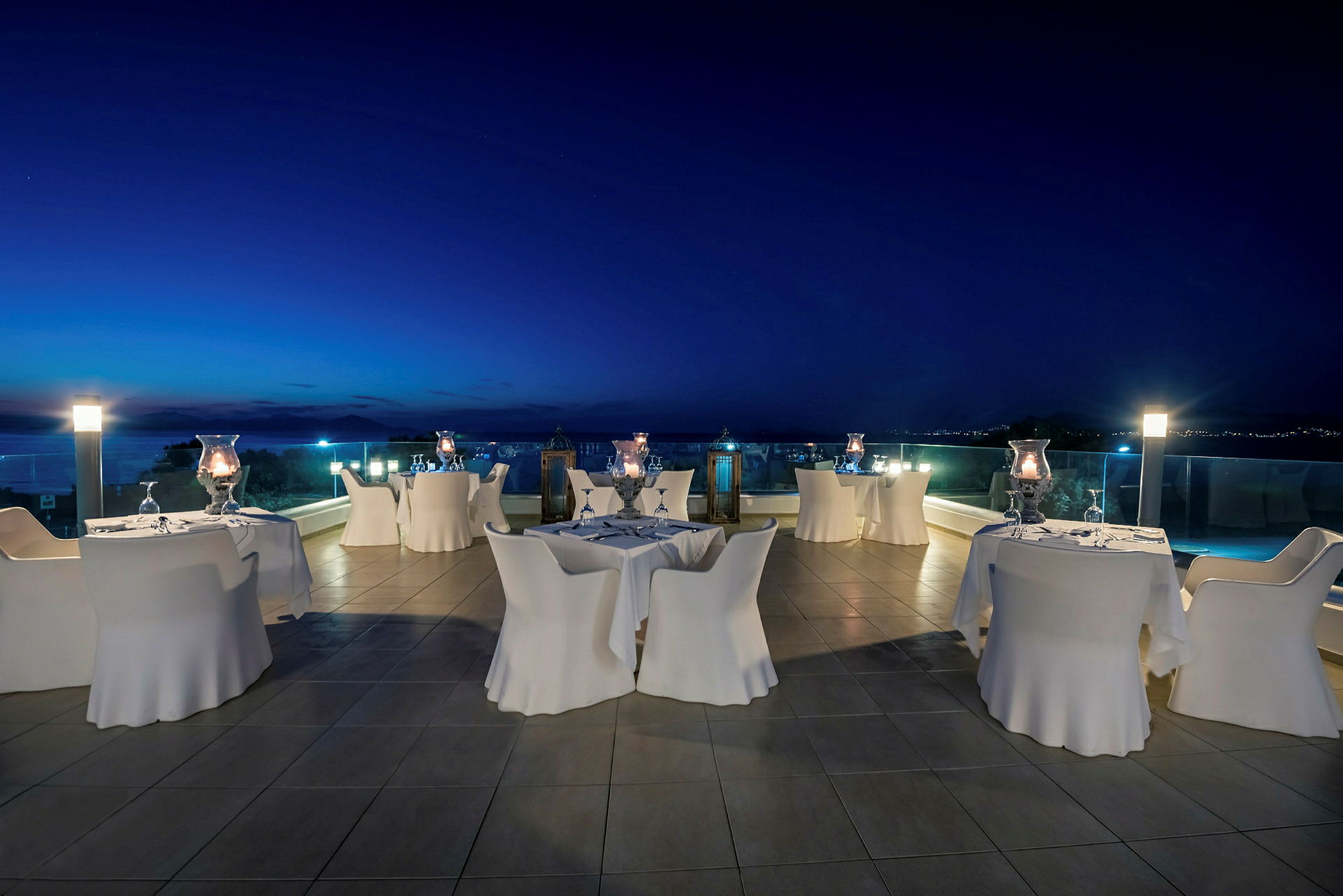 Smaksbord på terrasse med utsikt over havet ved skumring. (AI-generert tekst)