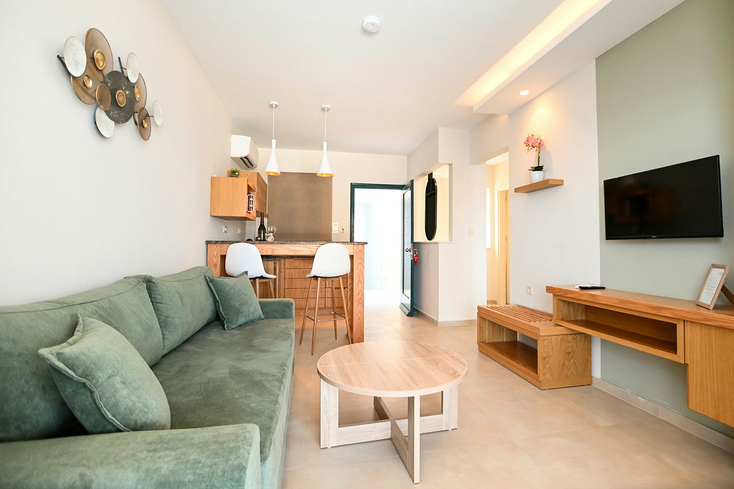 Et moderne oppholdsrom med grønn sofa, trebord og TV på veggen. (AI-generert tekst)