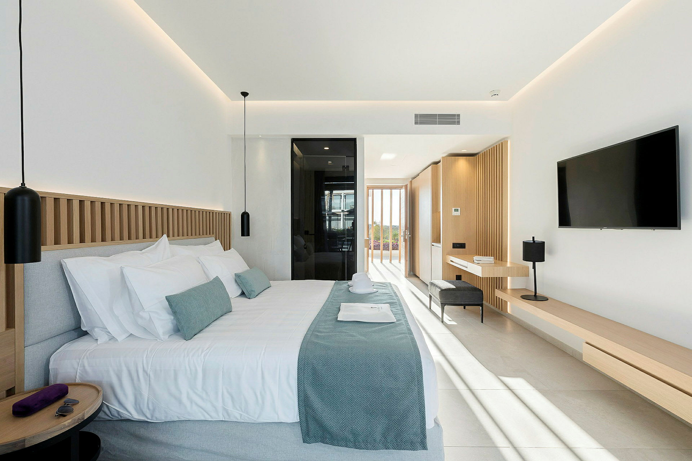 Moderne hotellrom med dobbeltseng, vindu i bakgrunnen og lyse toner i interiøret. (AI-generert tekst)