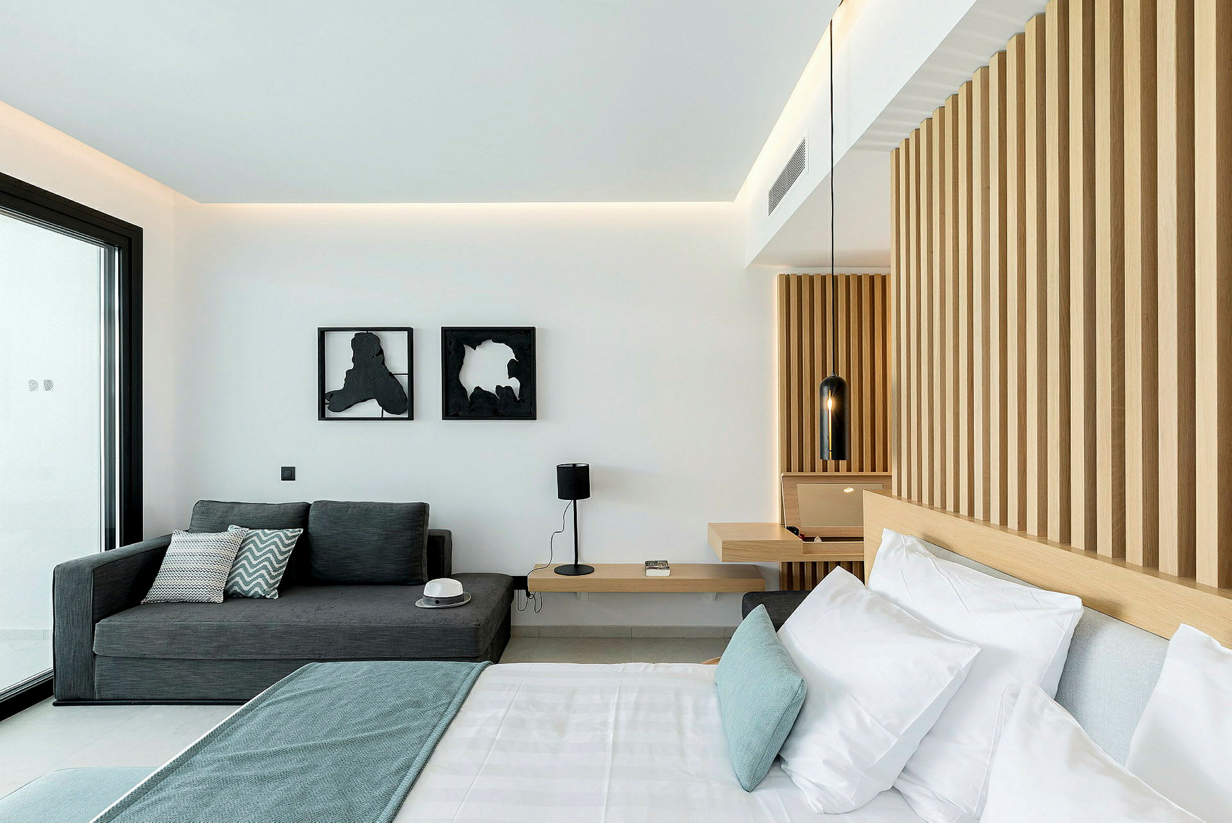 Et moderne hotellrom med en seng, en sofa og en vegg med trepanel. (AI-generert tekst)