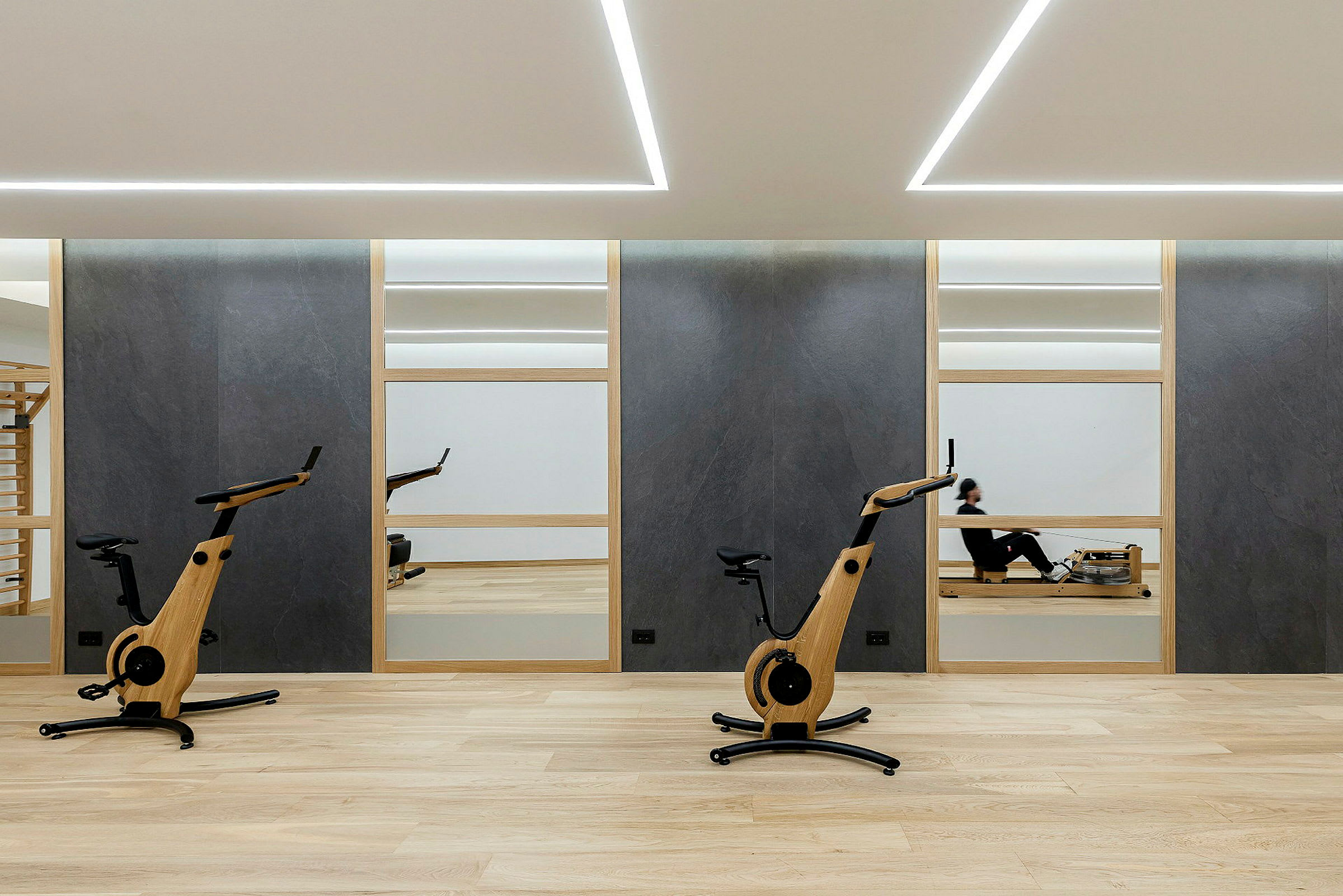 Gym med to treningssykler og en person på en romaskin. (AI-generert tekst)