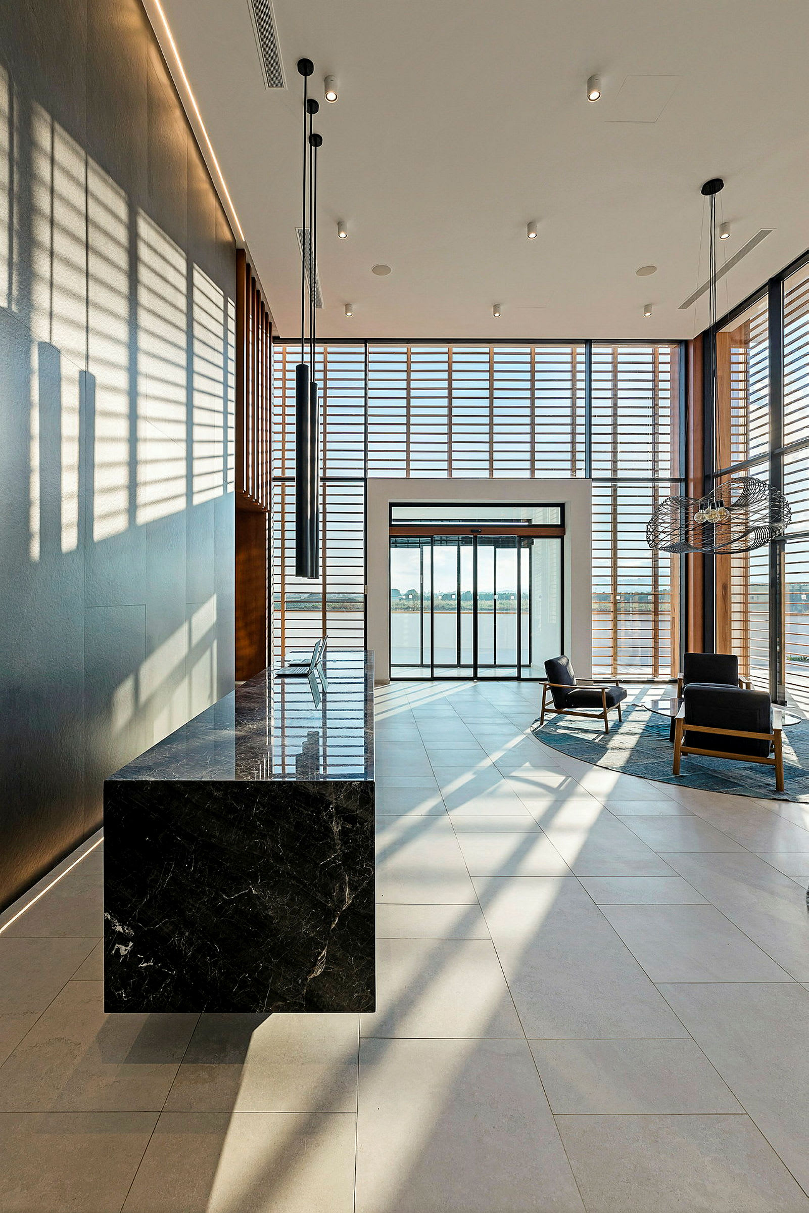 Moderne hotellobby med designmøbler og store vinduer som slipper inn dagslys. (AI-generert tekst)