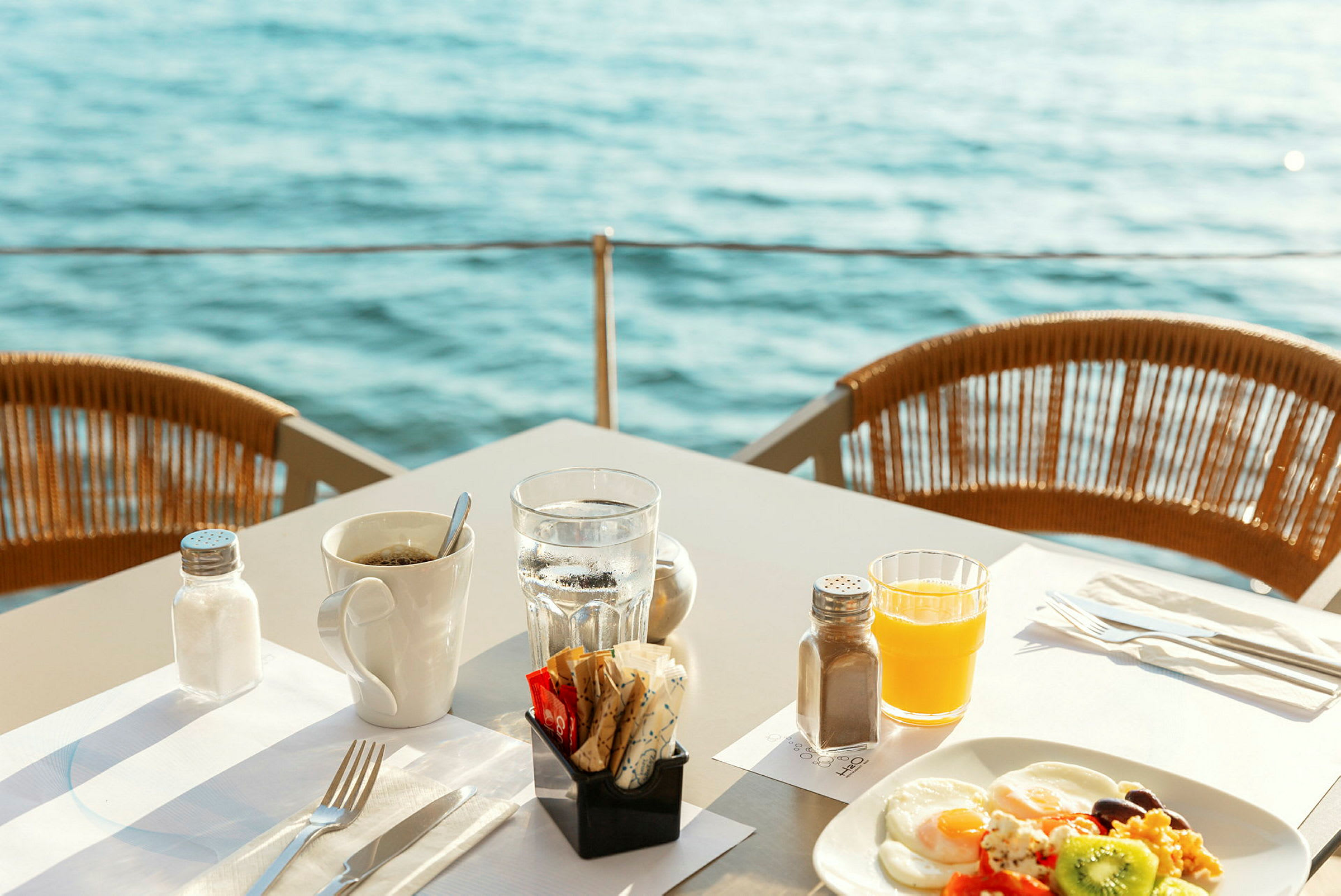 Frokost servert ved bord med utsikt over vannet. (AI-generert tekst)