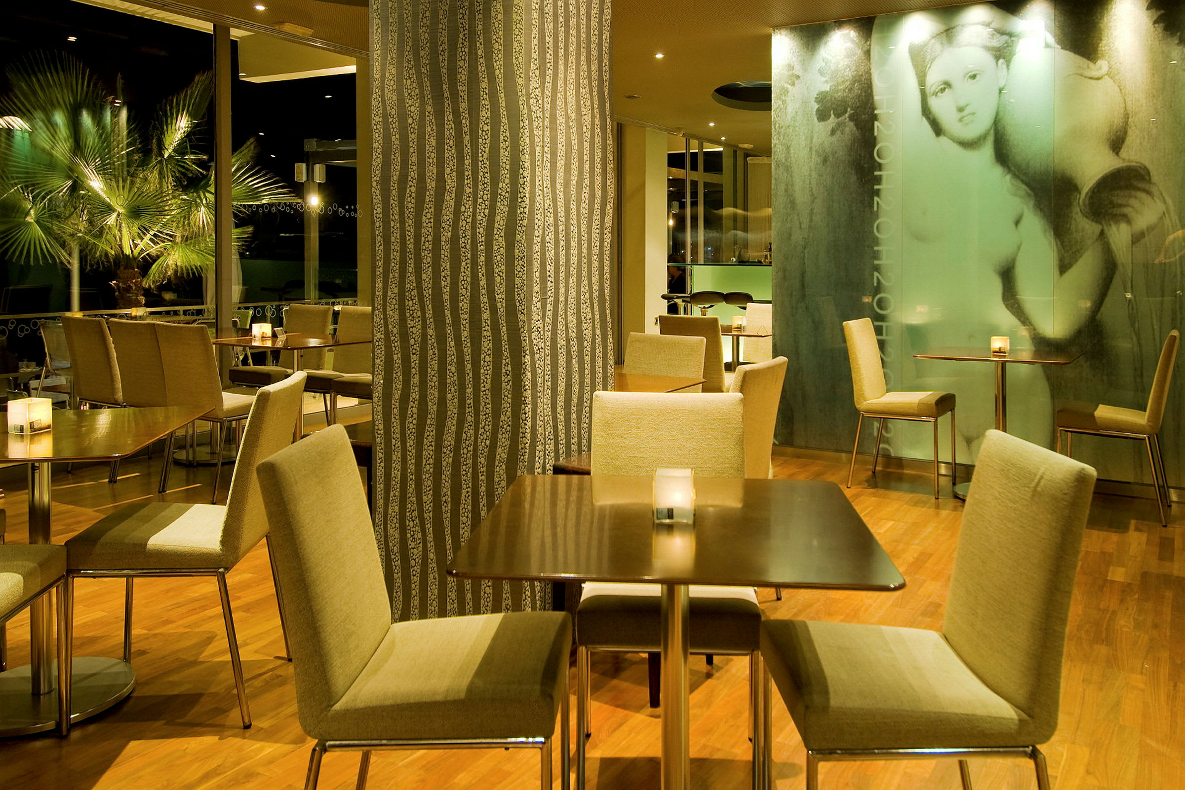 En restaurantinteriør med bord og stoler på et tregulv, omgitt av dekorative vegger og planter. (AI-generert tekst)