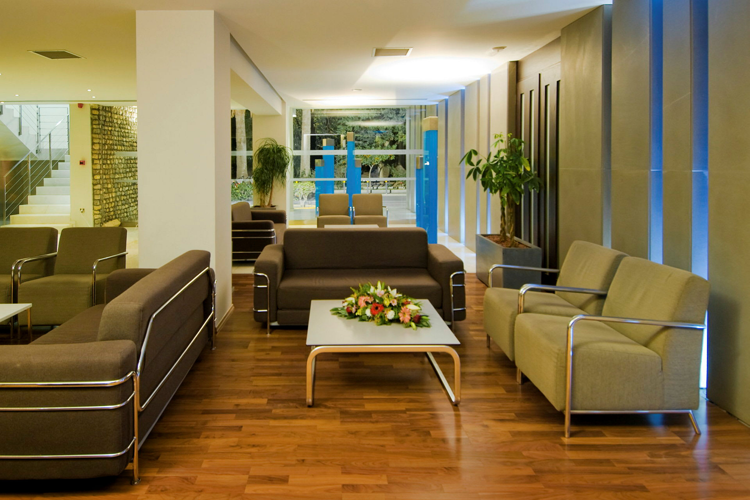 Et moderne loungeområde med sofaer, lenestoler og et bord med blomster på. (AI-generert tekst)