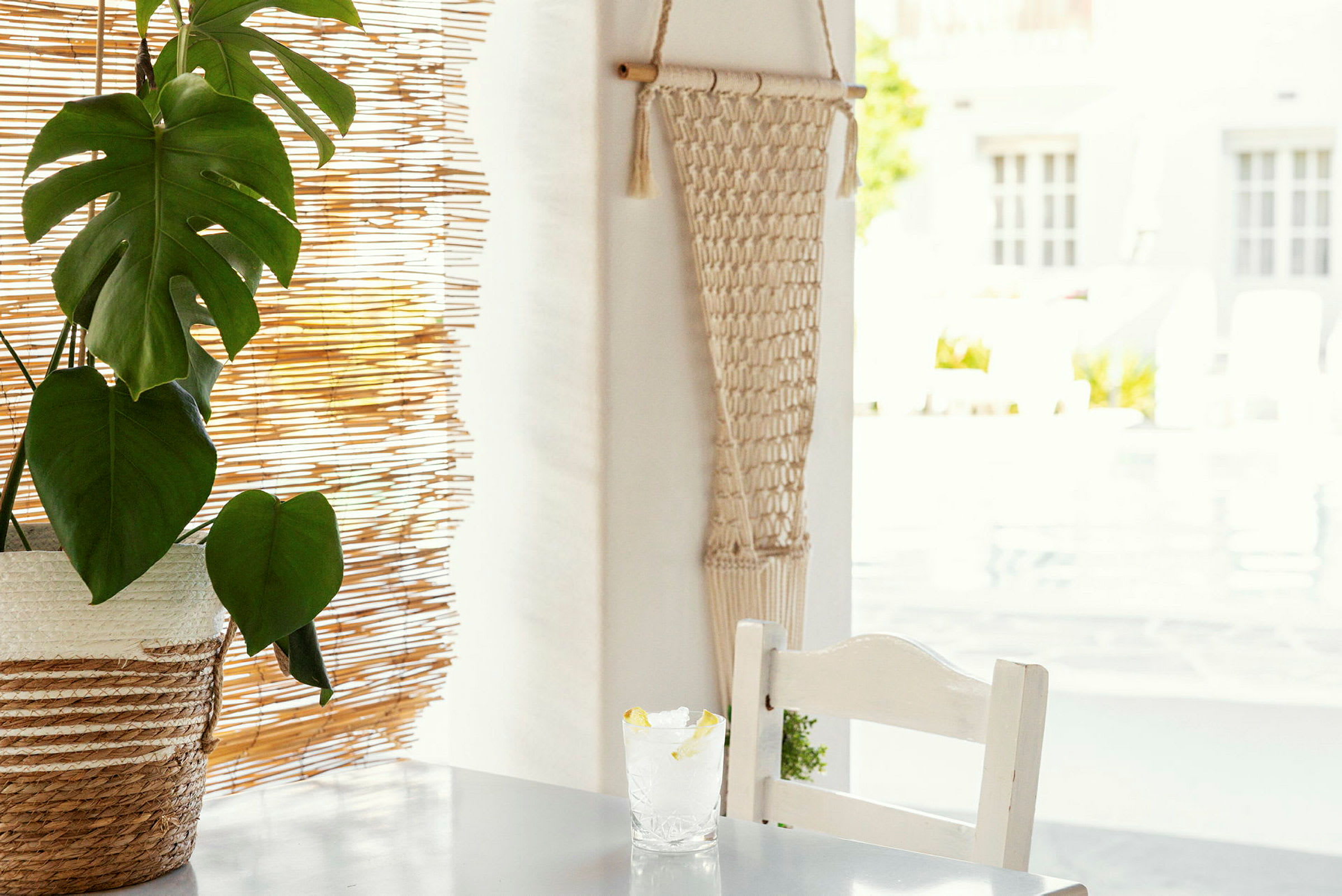 Bord med plante og glass med sitron ved siden av bambuspersienne. (AI-generert tekst)