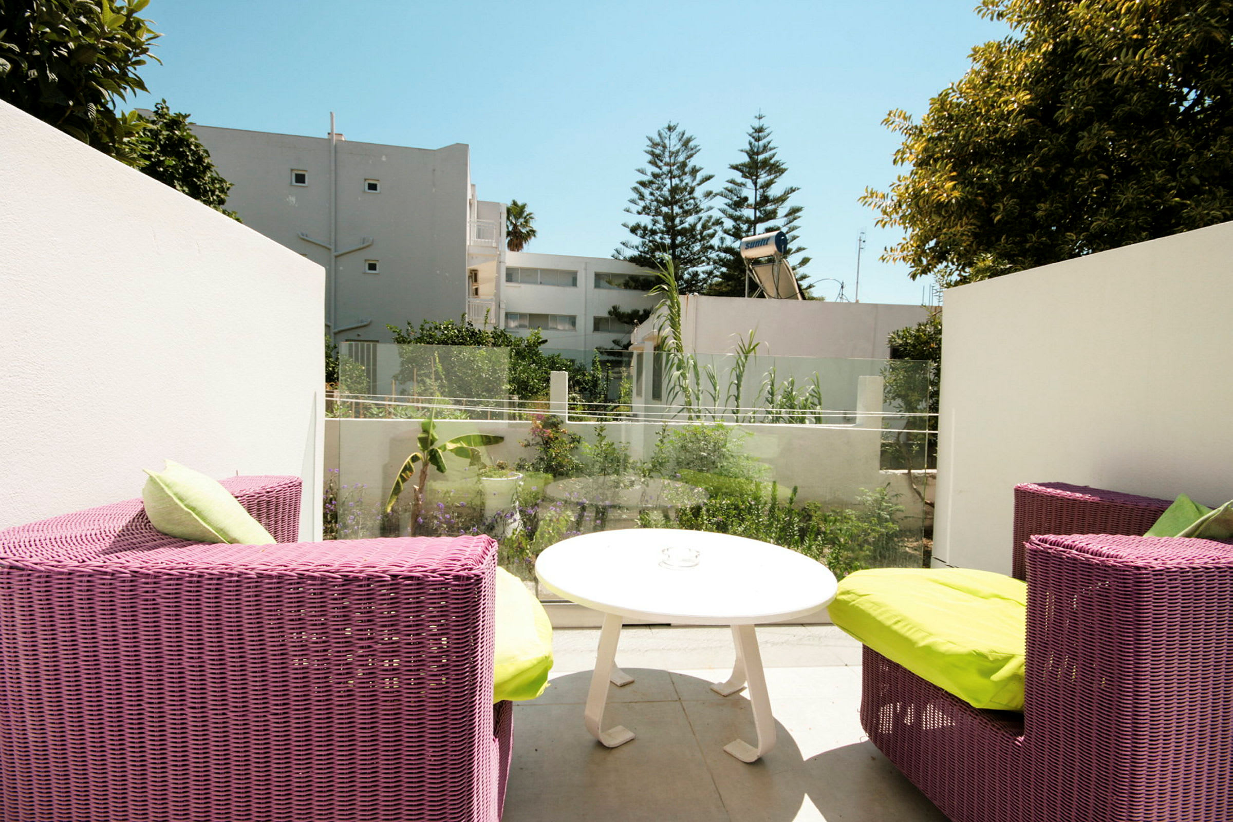 Terrasse med rosa rottingmøbler og grønn vegetasjon i bakgrunnen. (AI-generert tekst)