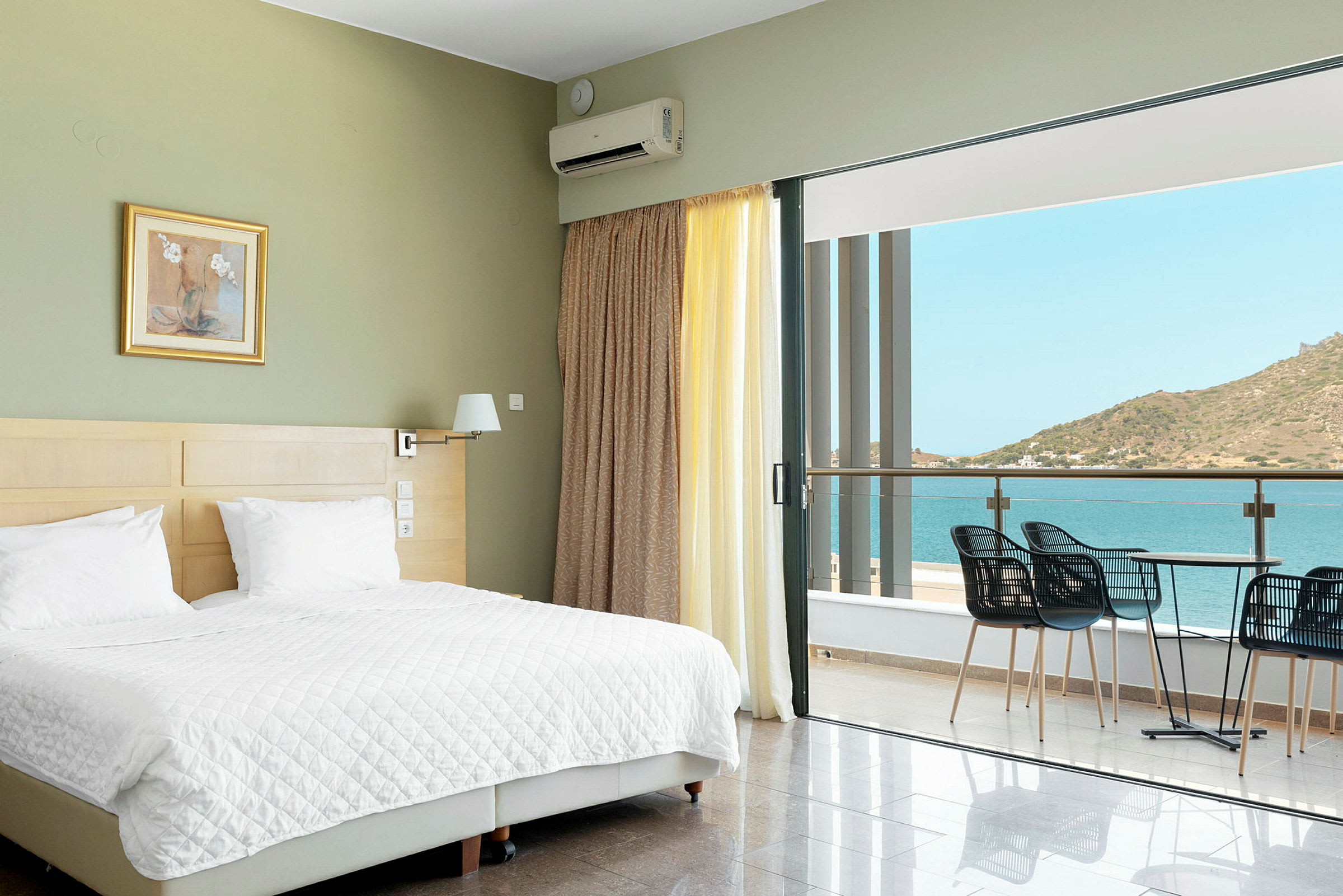 Hotellrom med en dobbeltseng og en balkong med utsikt over havet. (AI-generert tekst)