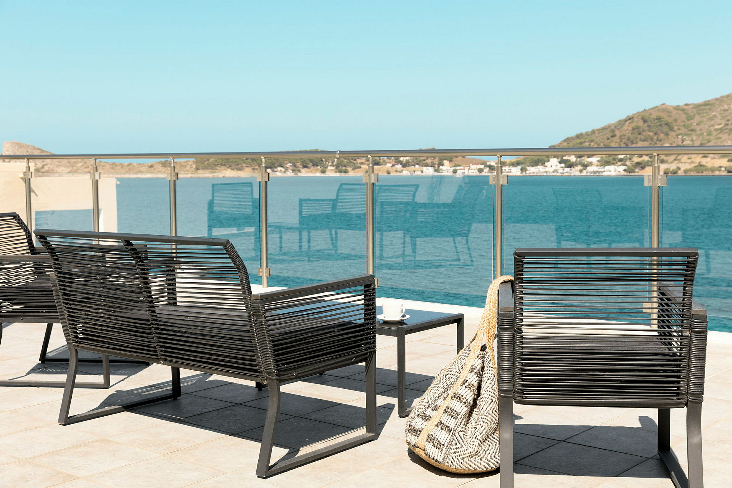 Utemøbler på en terrasse med utsikt over havet og det omkringliggende landskapet. (AI-generert tekst)