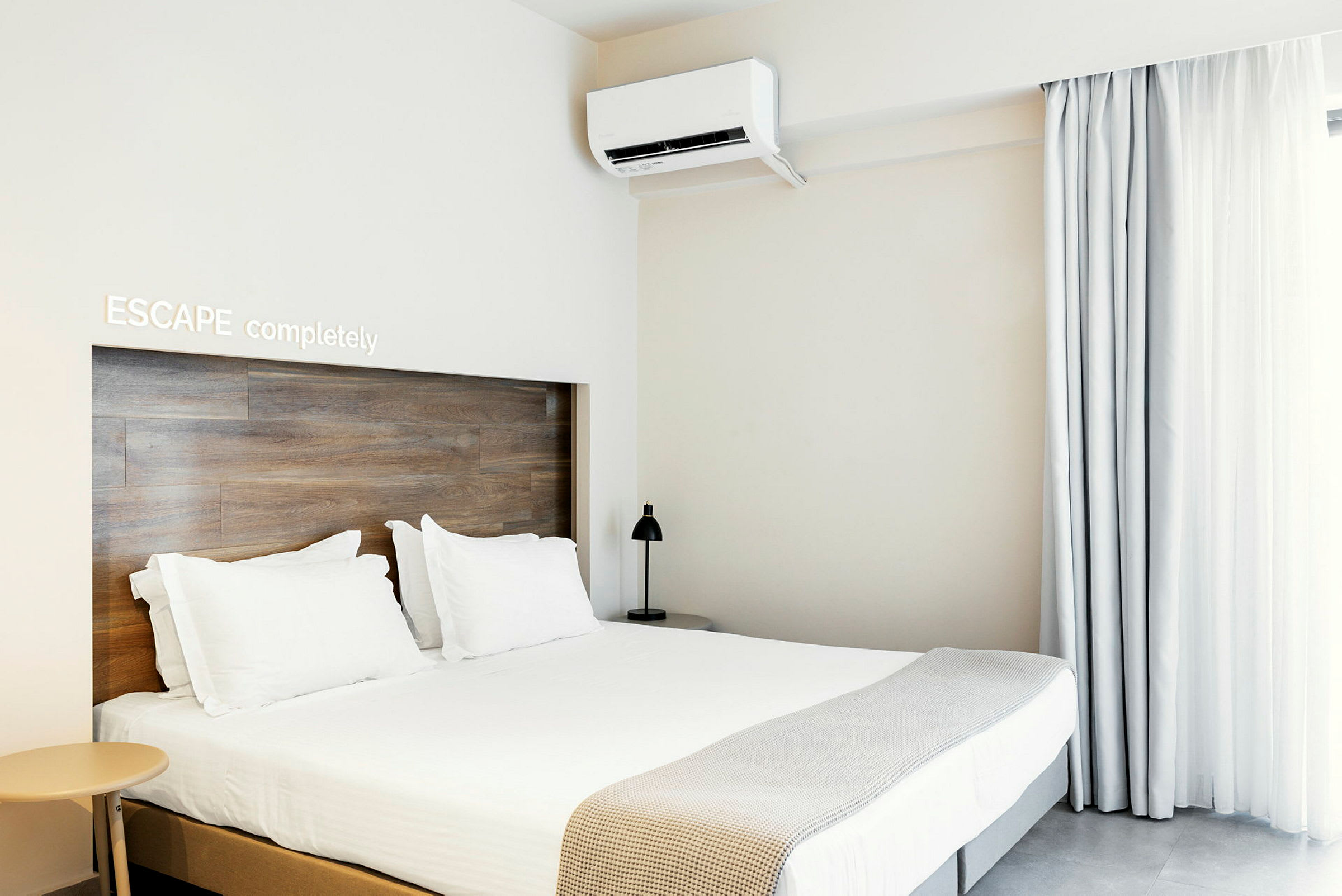 Et moderne hotellrom med dobbeltseng, lys innredning og klimaanlegg. (AI-generert tekst)