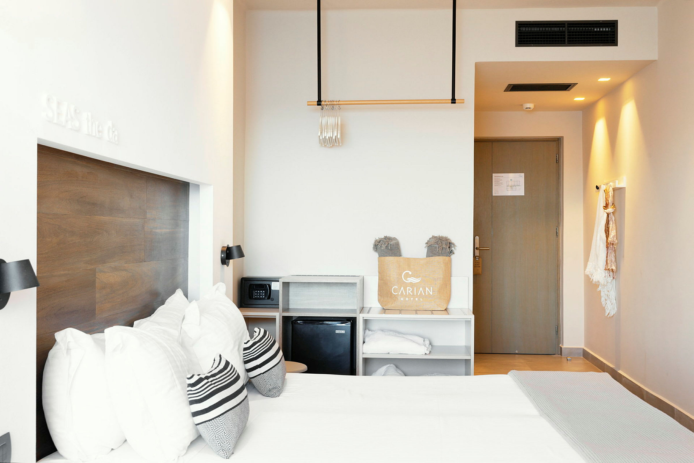 Et hotellrom med en dobbeltseng, trepanel på veggen, oppbevaringshyller og en dør. (AI-generert tekst)