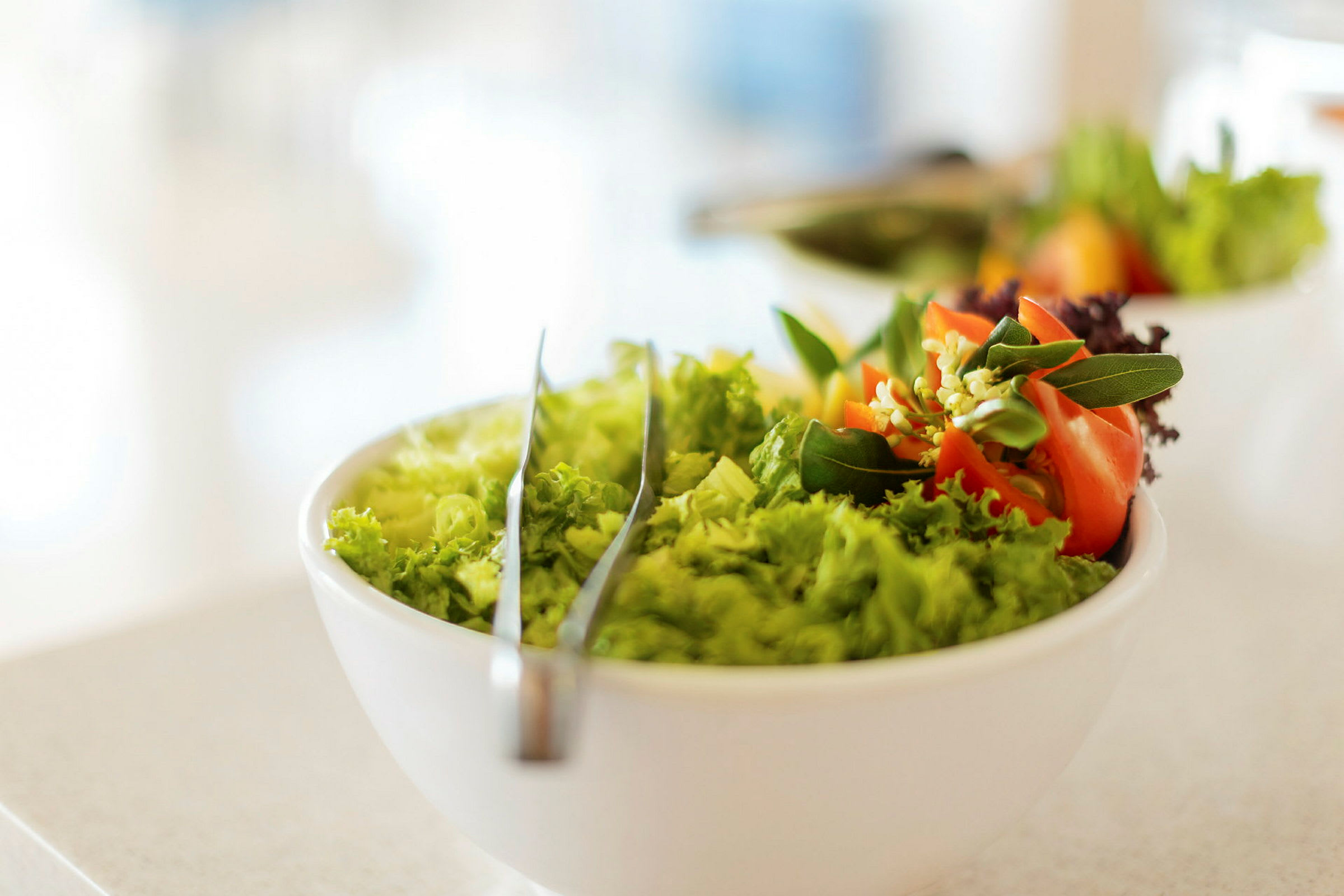 En salat i en hvit bolle med dekorative grønnsaker. (AI-generert tekst)
