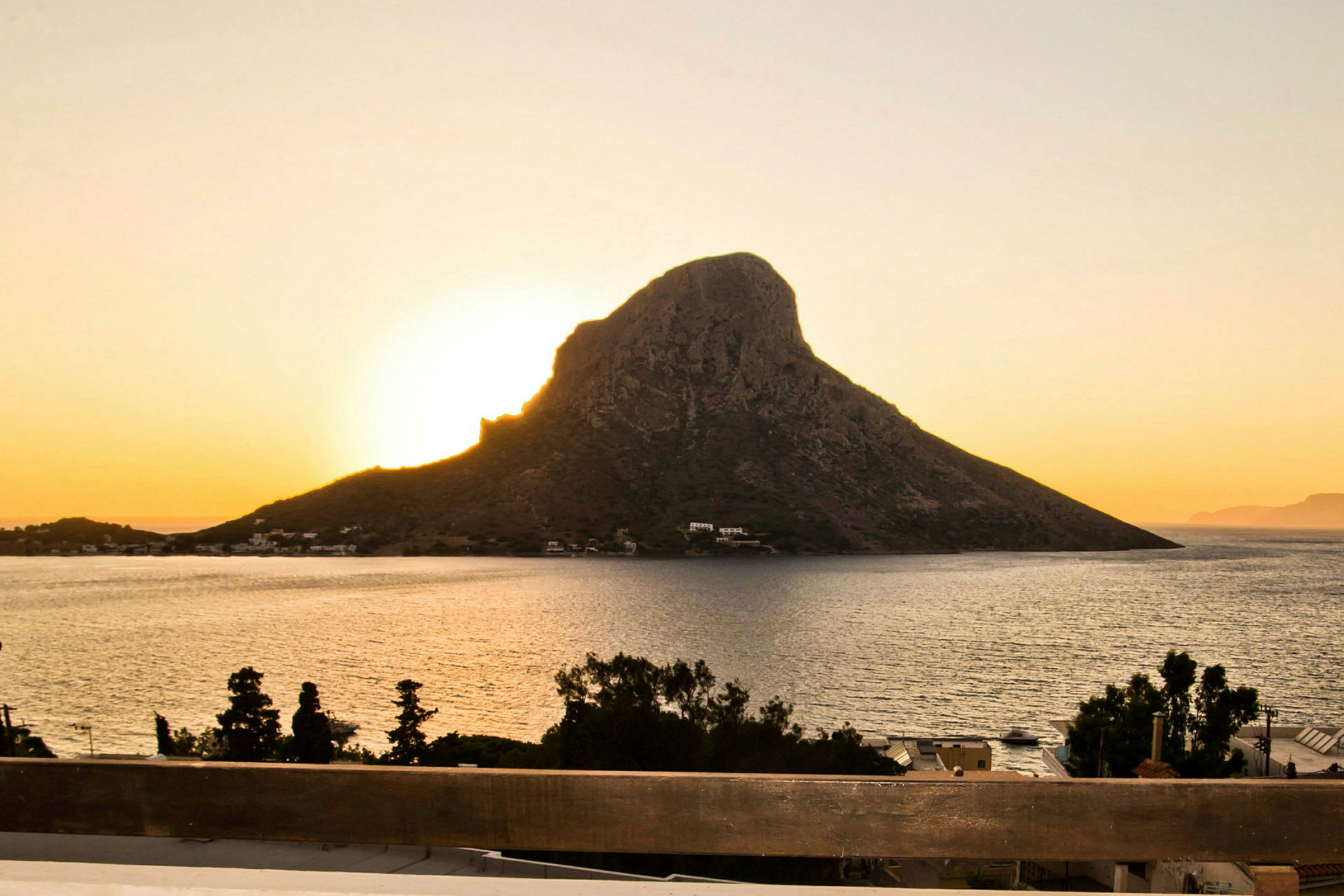 Solnedgang bak en klippe ved havet. (AI-generert tekst)