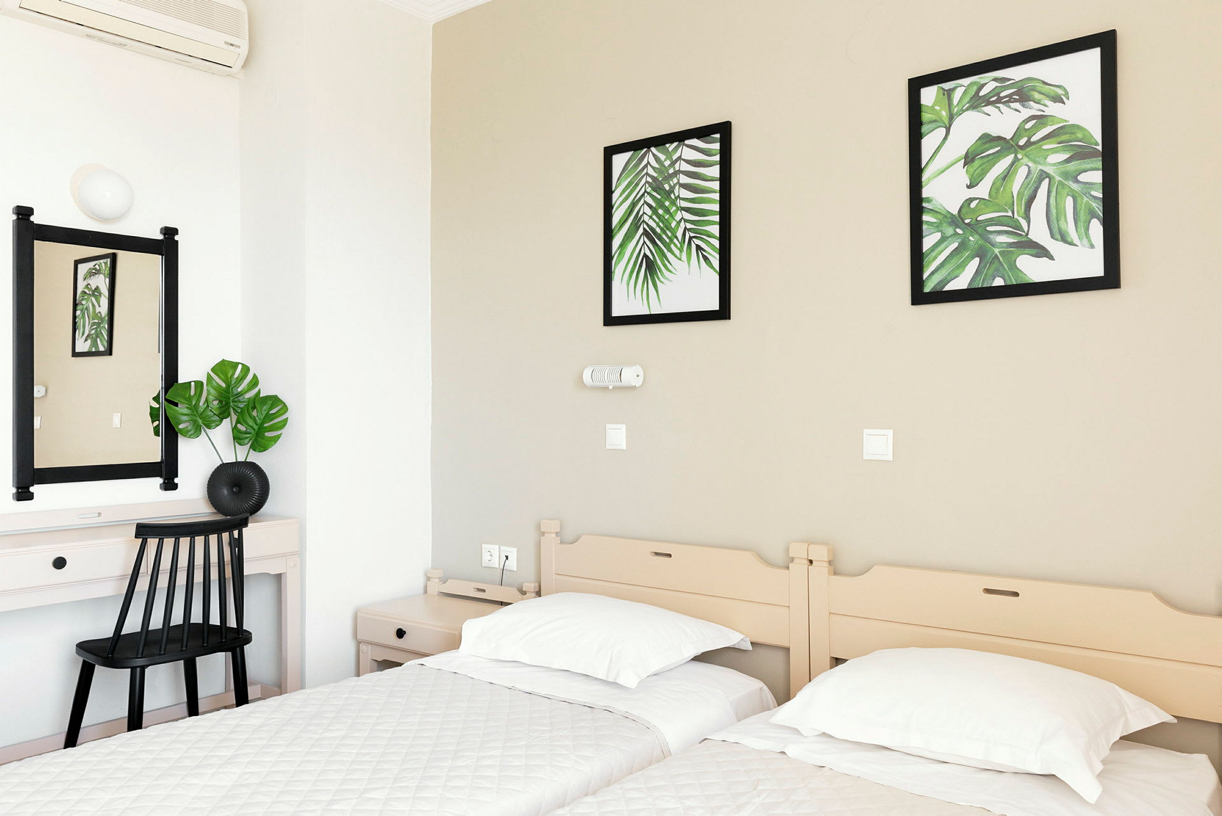 Hotellrom med to enkeltsenger, et skrivebord og veggdekorasjoner med botaniske motiver. (AI-generert tekst)