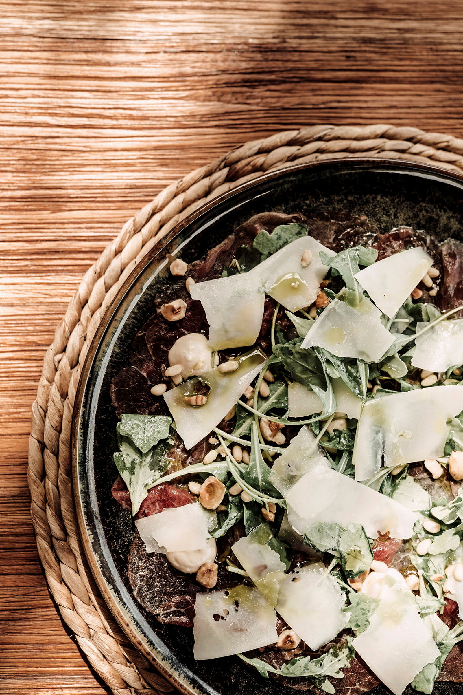 Nærbilde av en salat med ruccola, tynne osteskiver, nøtter og balsamicodressing. (AI-generert tekst)