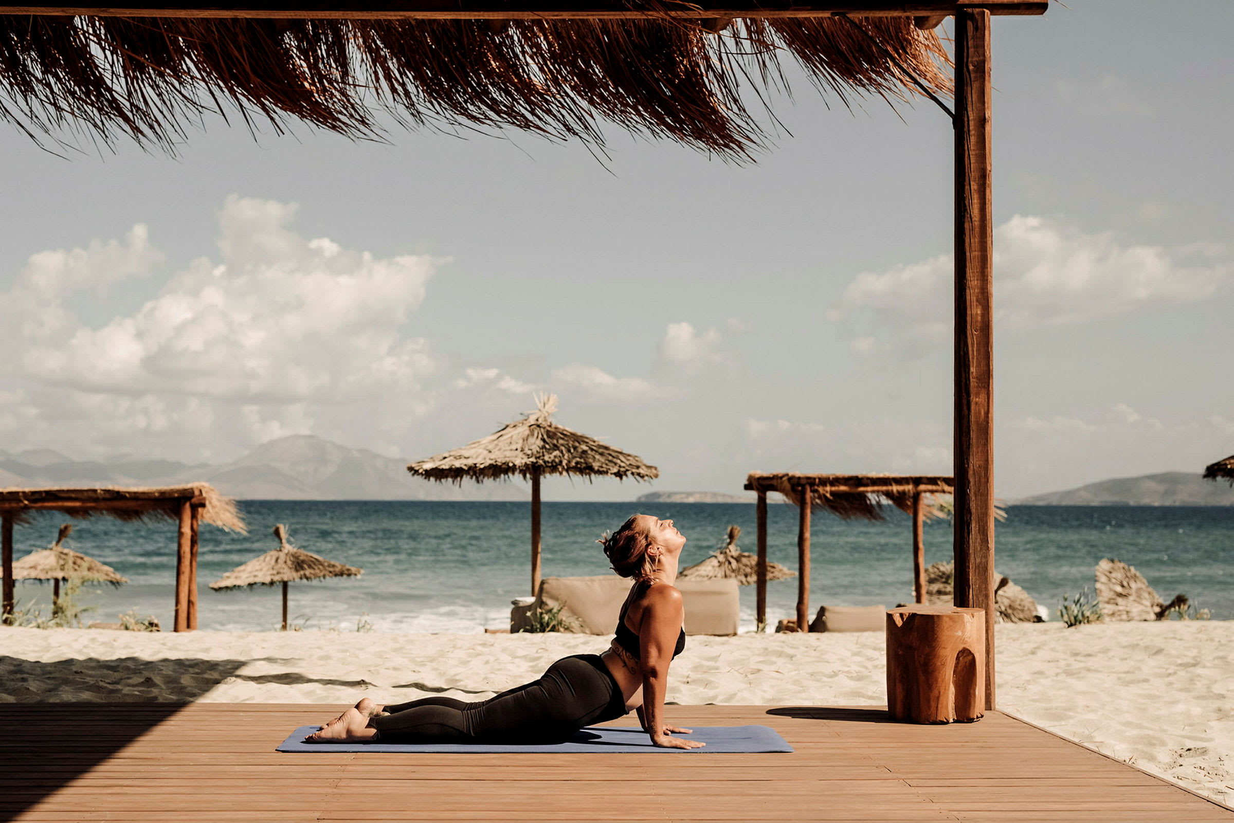 Person på en treplattform ved stranden og havet, utfører yoga. (AI-generert tekst)