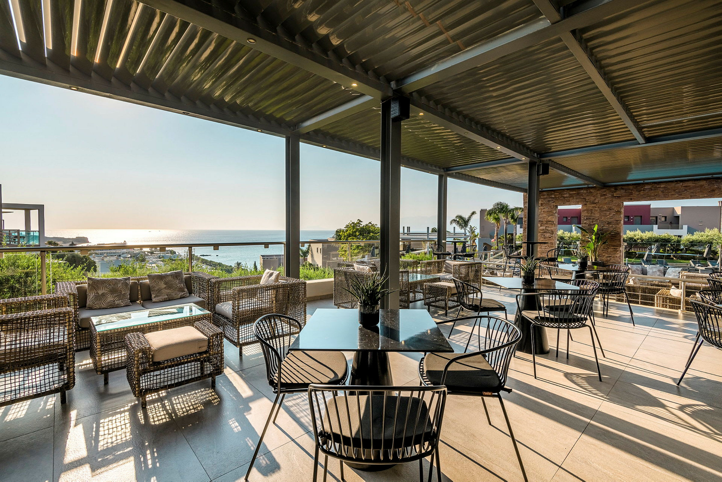 Utendørs terrasse med sittegrupper og utsikt mot havet. (AI-generert tekst)