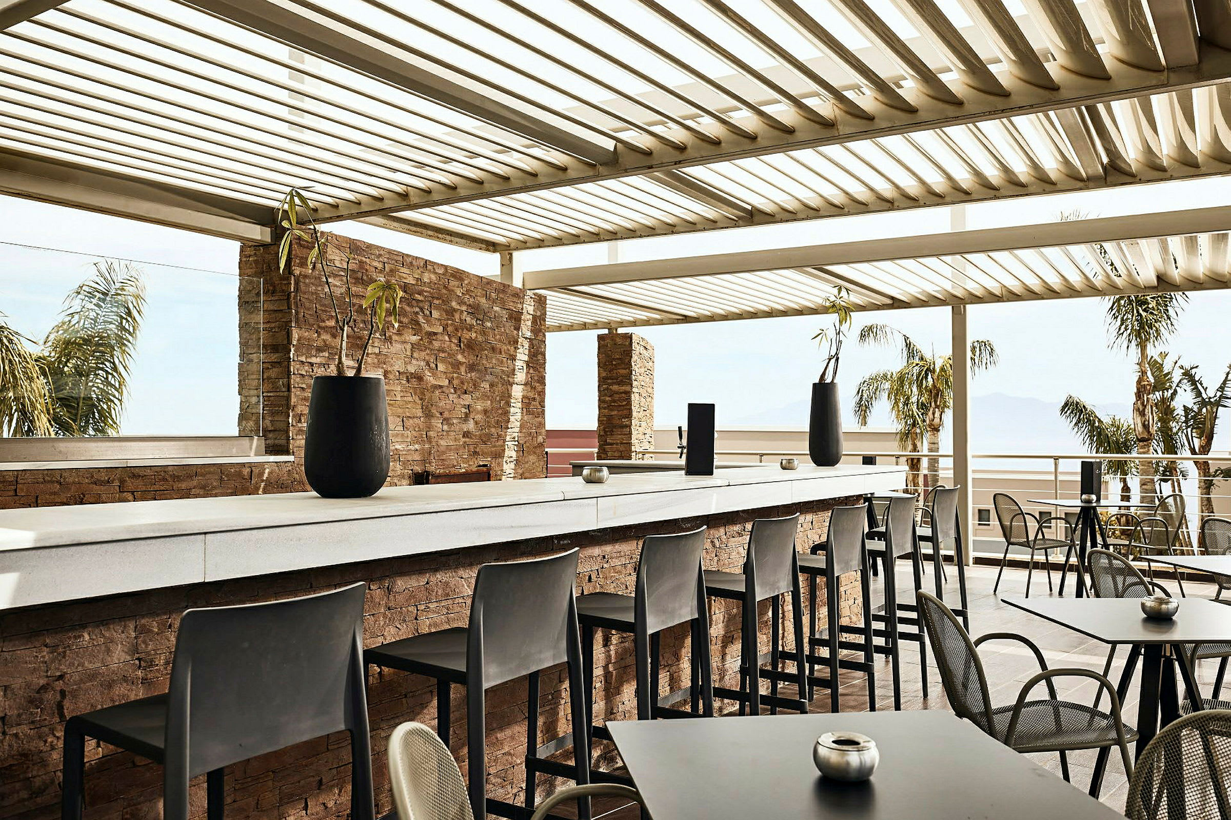 Utendørs serveringsområde med bord, stoler og en bar under tak. (AI-generert tekst)