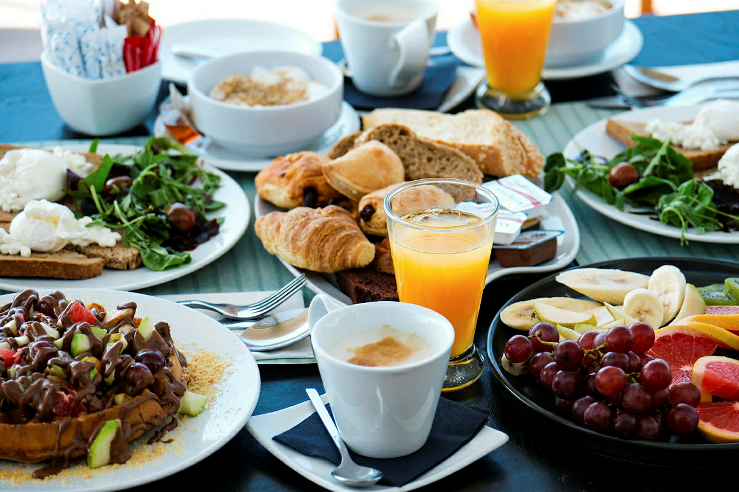 En frokostbuffé med brød, wienerbrød, frukt, salat, appelsinjuice og kaffe. (AI-generert tekst)