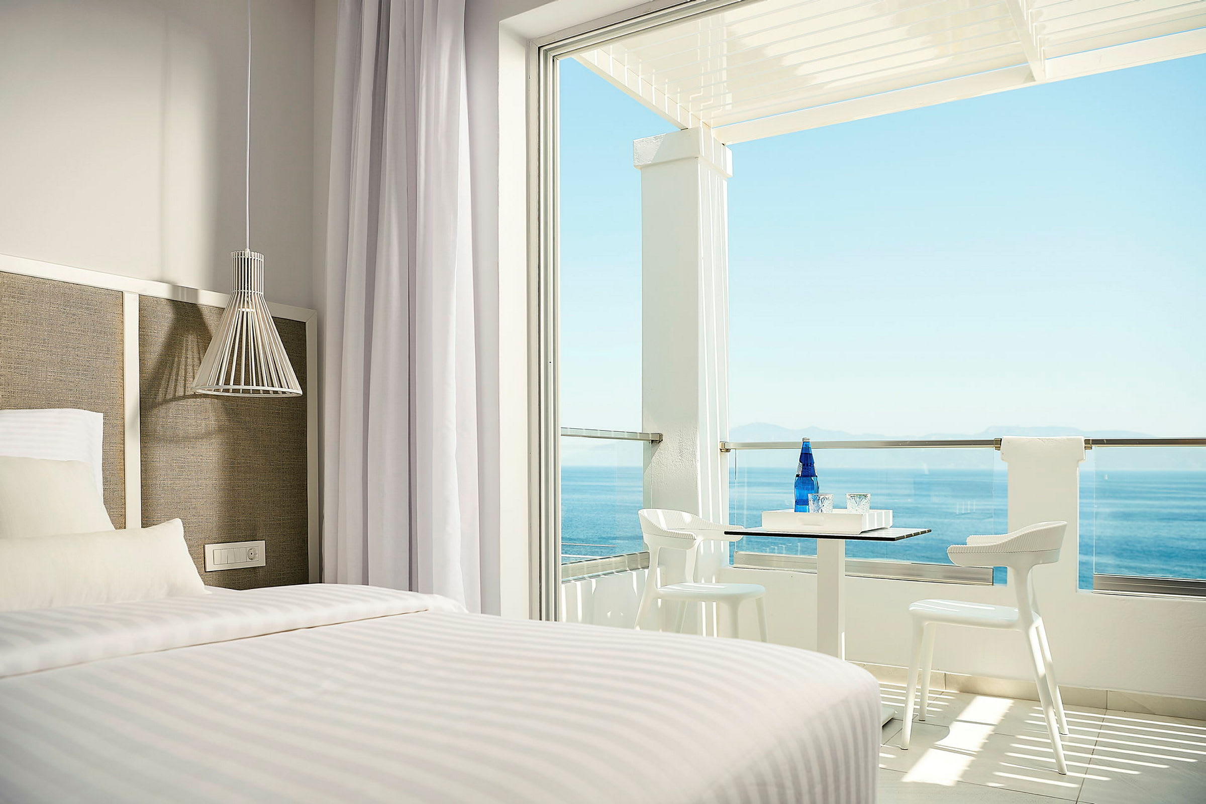 Hotellrom med seng og uteplass med havutsikt. (AI-generert tekst)