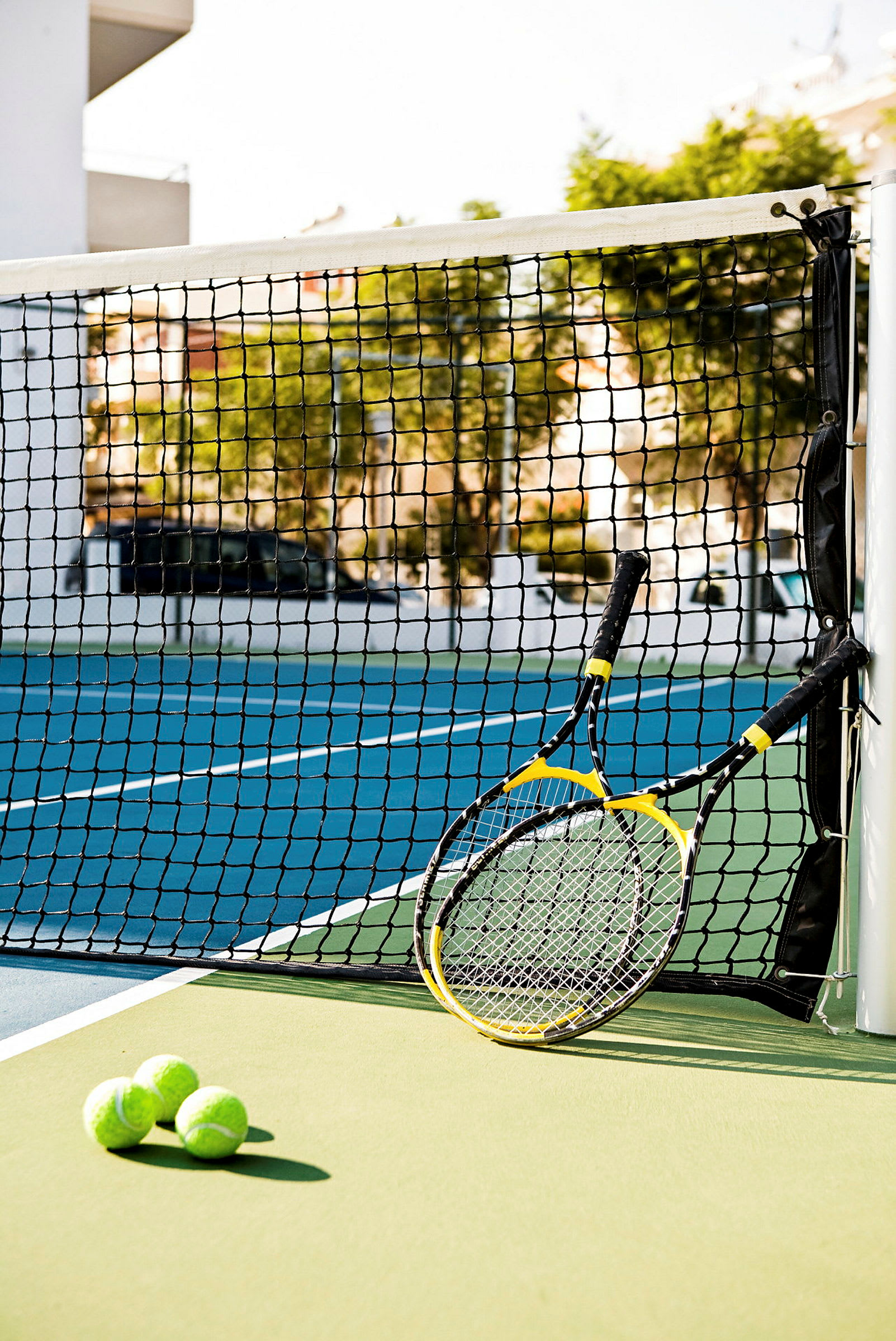 To tennisracketer og tre tennisballer ved et nett på en tennisbane. (AI-generert tekst)