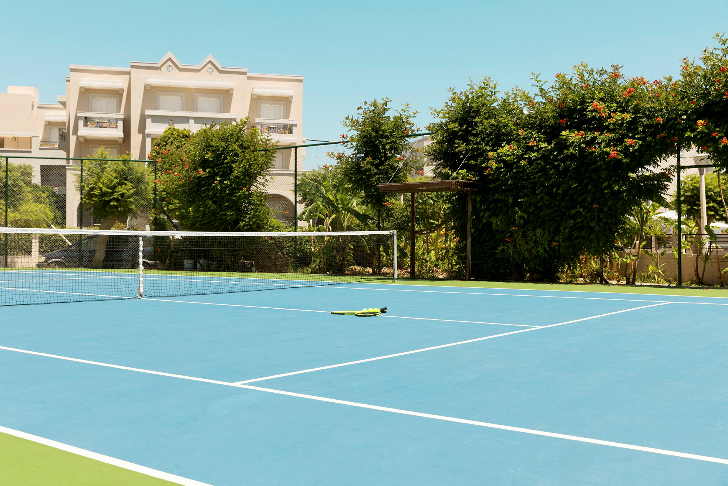 En tennisbane med et nett og grønn vegetasjon rundt. (AI-generert tekst)
