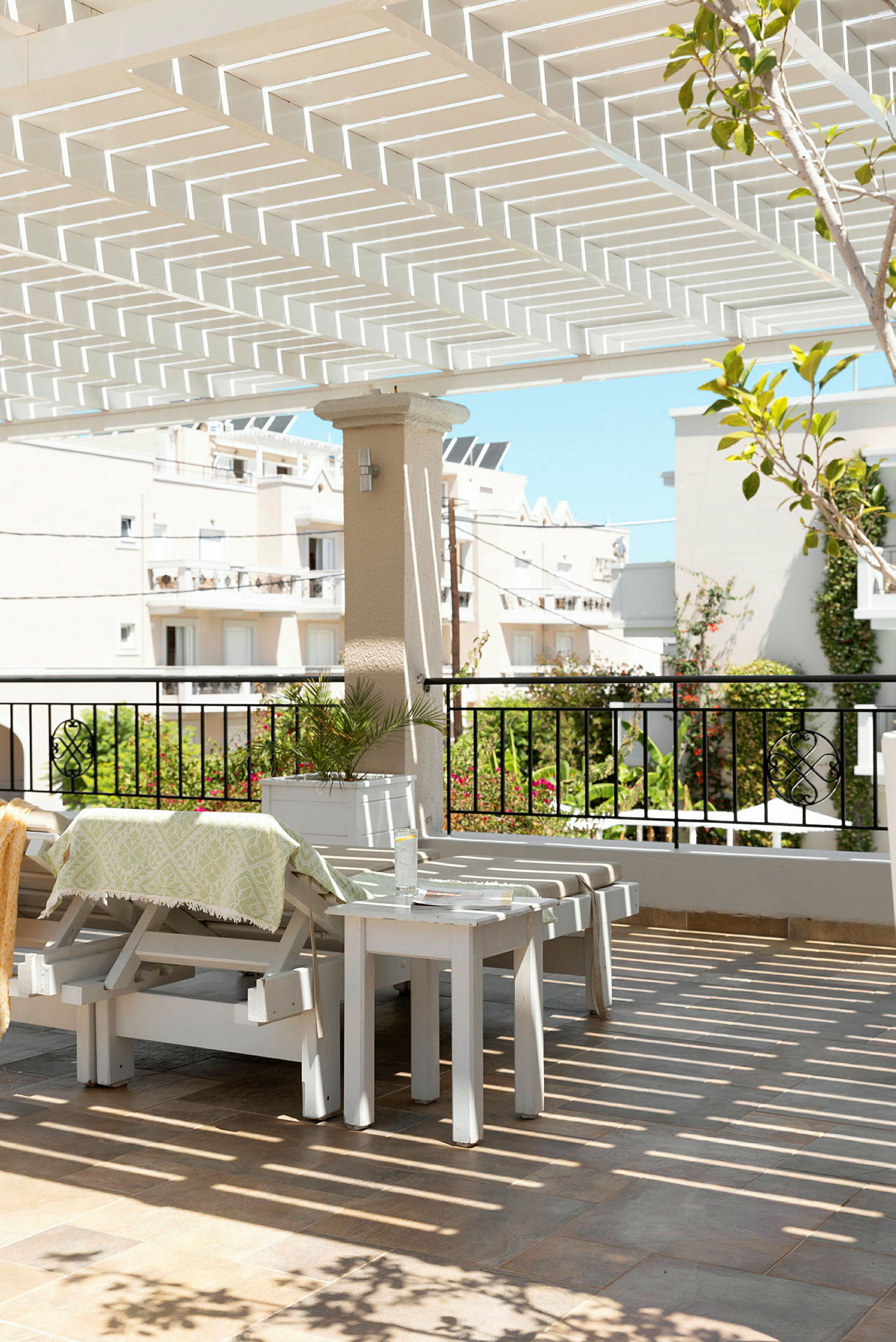 Utendørsområde med hvit pergola, utemøbler og utsikt mot bygninger og grøntområder. (AI-generert tekst)